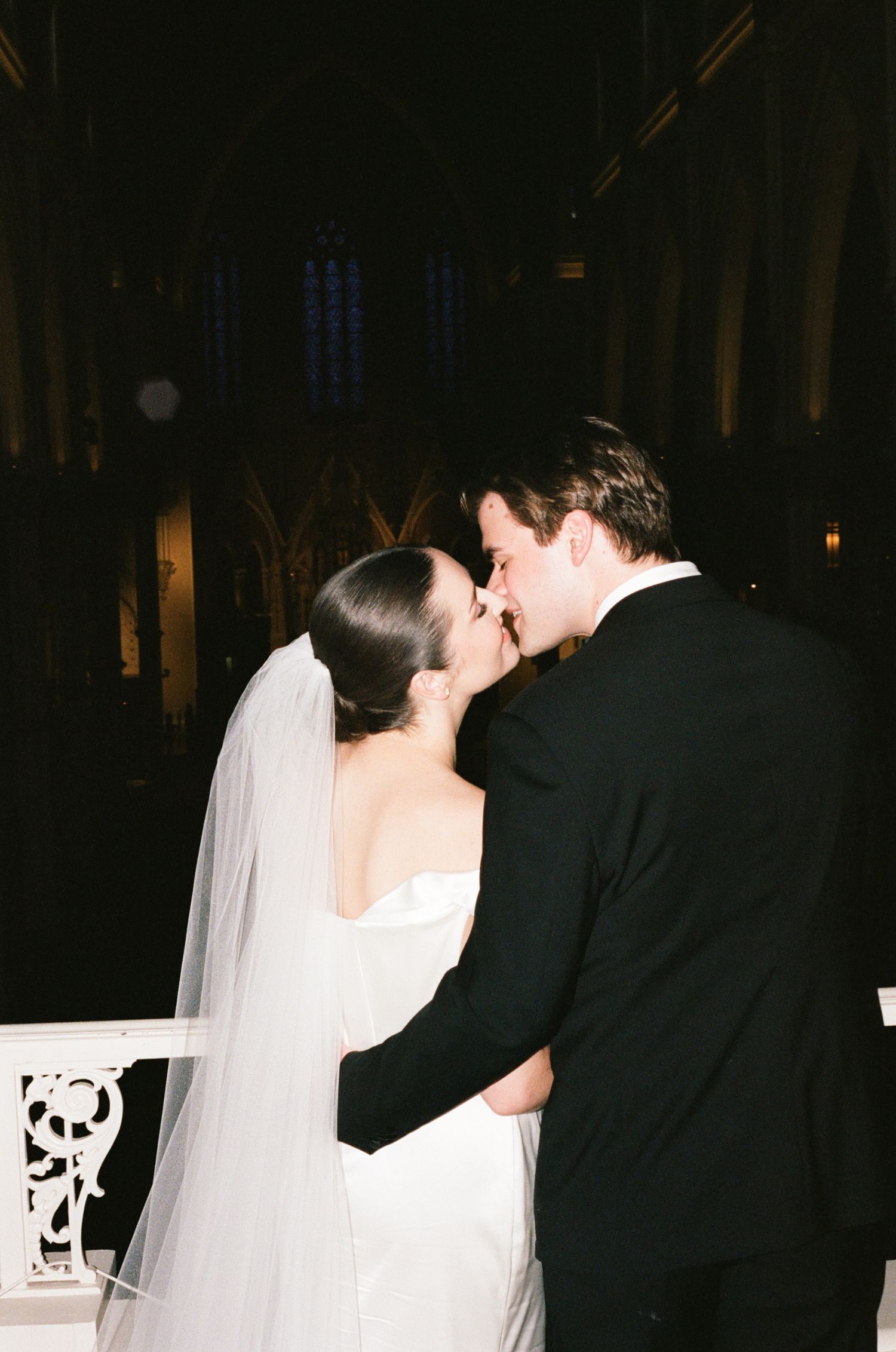 Bride and groom share their first kiss at the altar during a romantic wedding ceremony in a grand church.