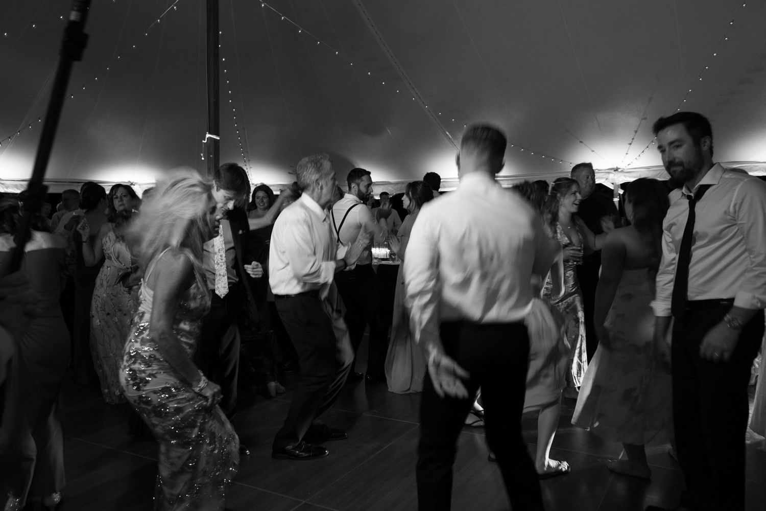 Wedding guests dancing and celebrating in a dark reception venue.