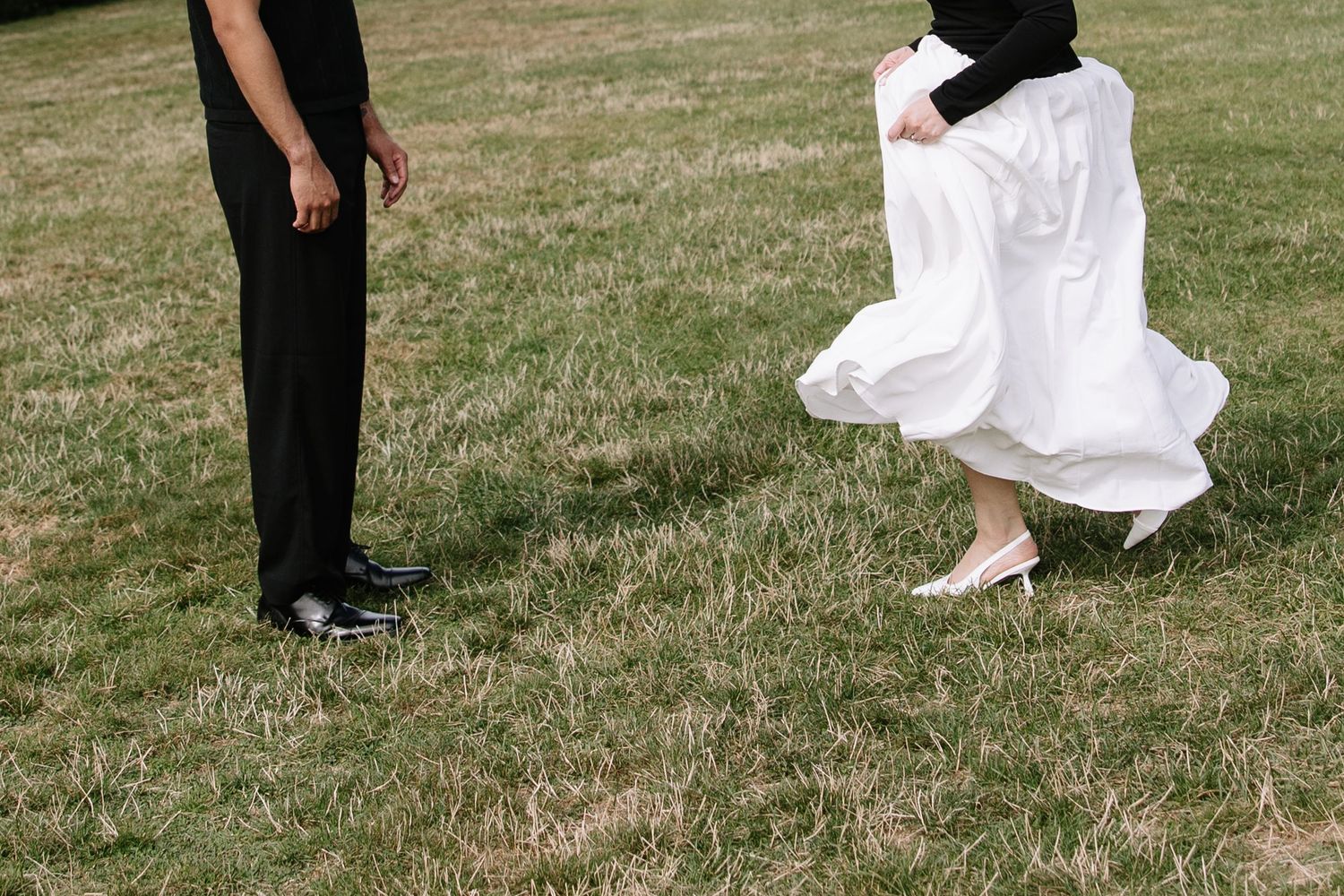 A flowing white dress and black suit captured in motion on grass.