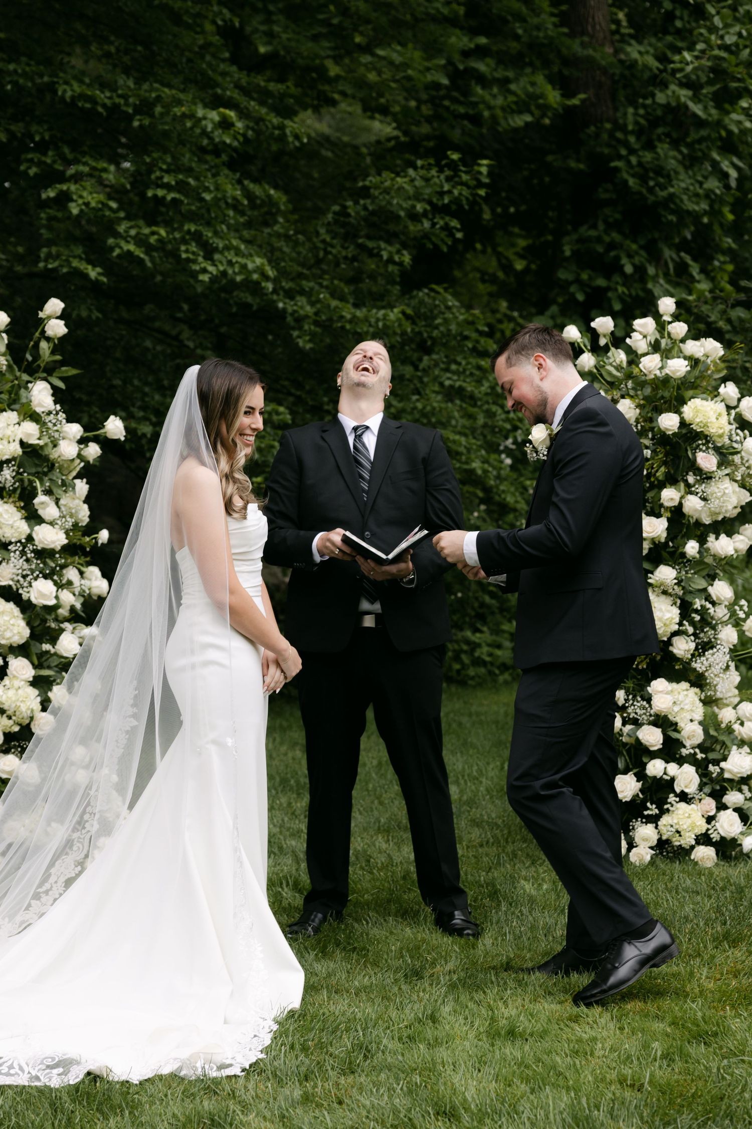 A wedding ceremony in progress with beautiful white floral arrangements framing the altar.