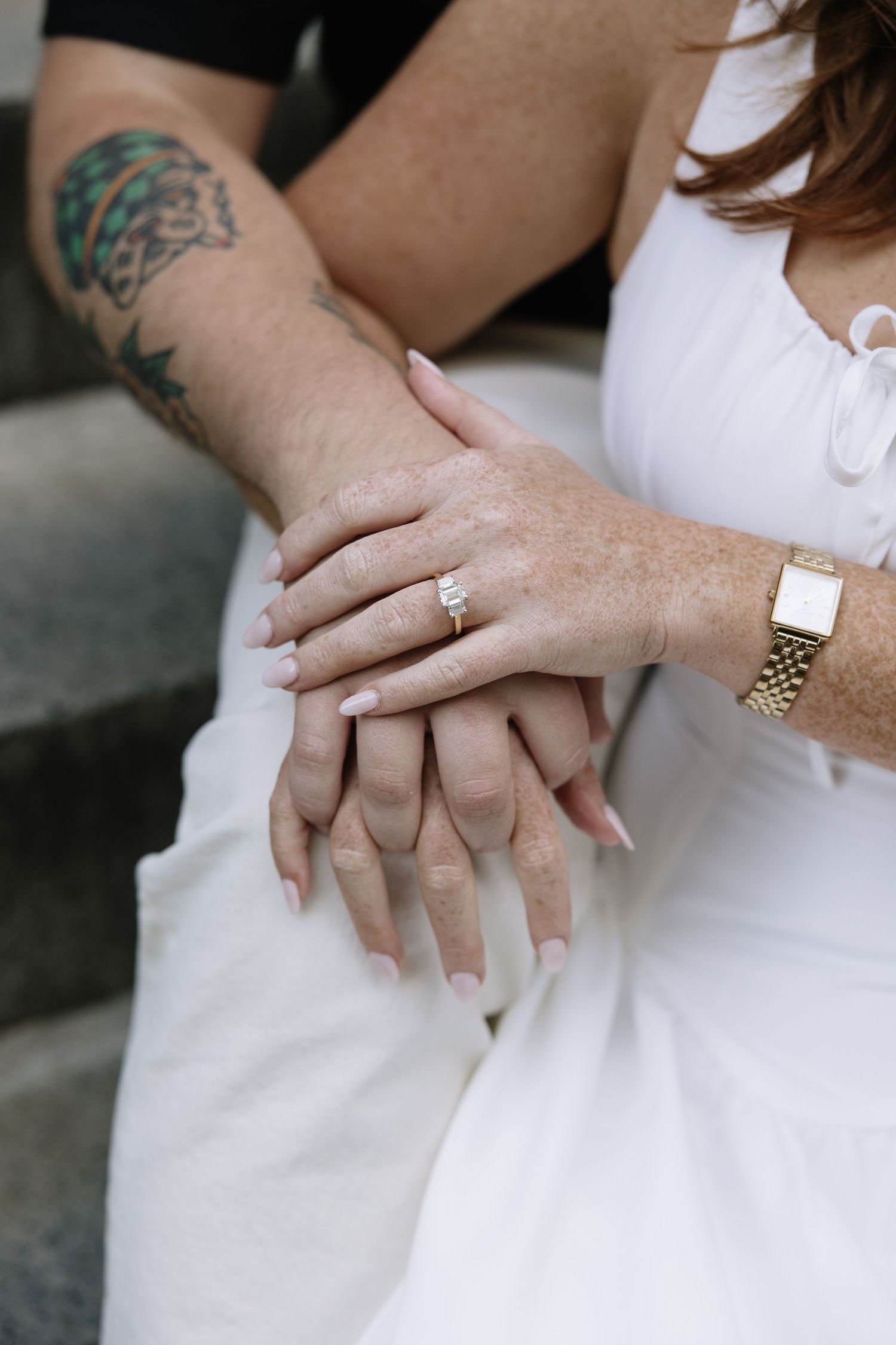 Close-up details of wedding rings and hands against white fabric.