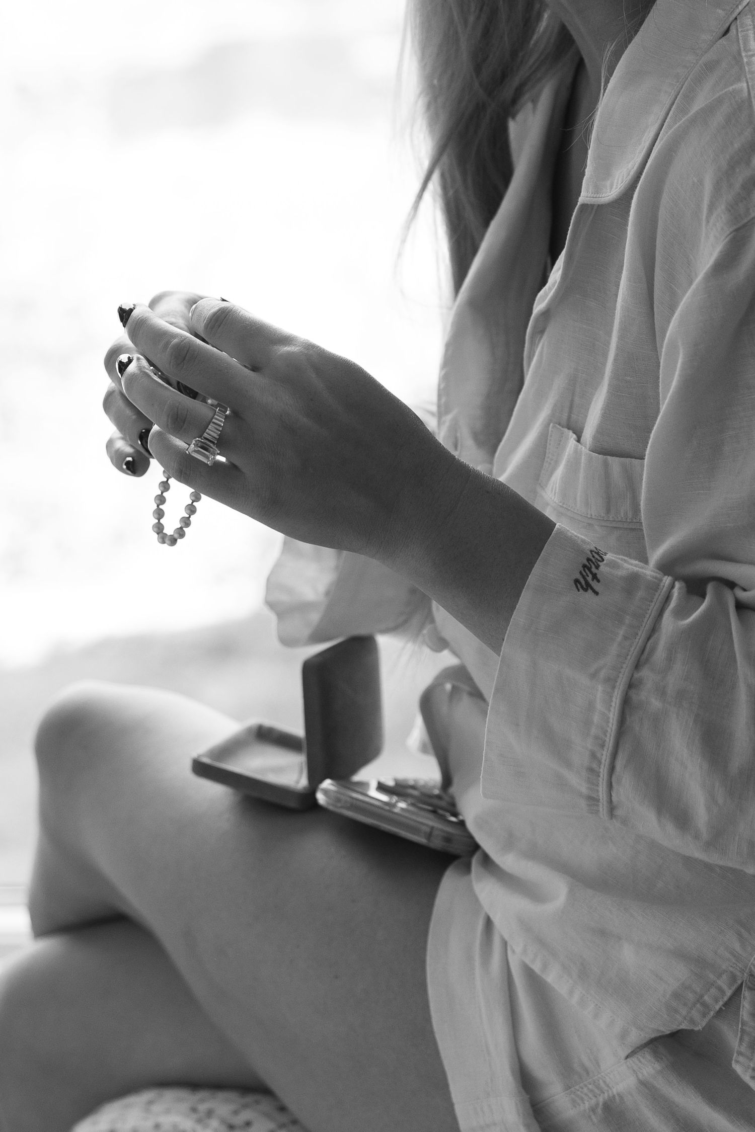 Black and white image of hands holding jewelry during wedding preparations.