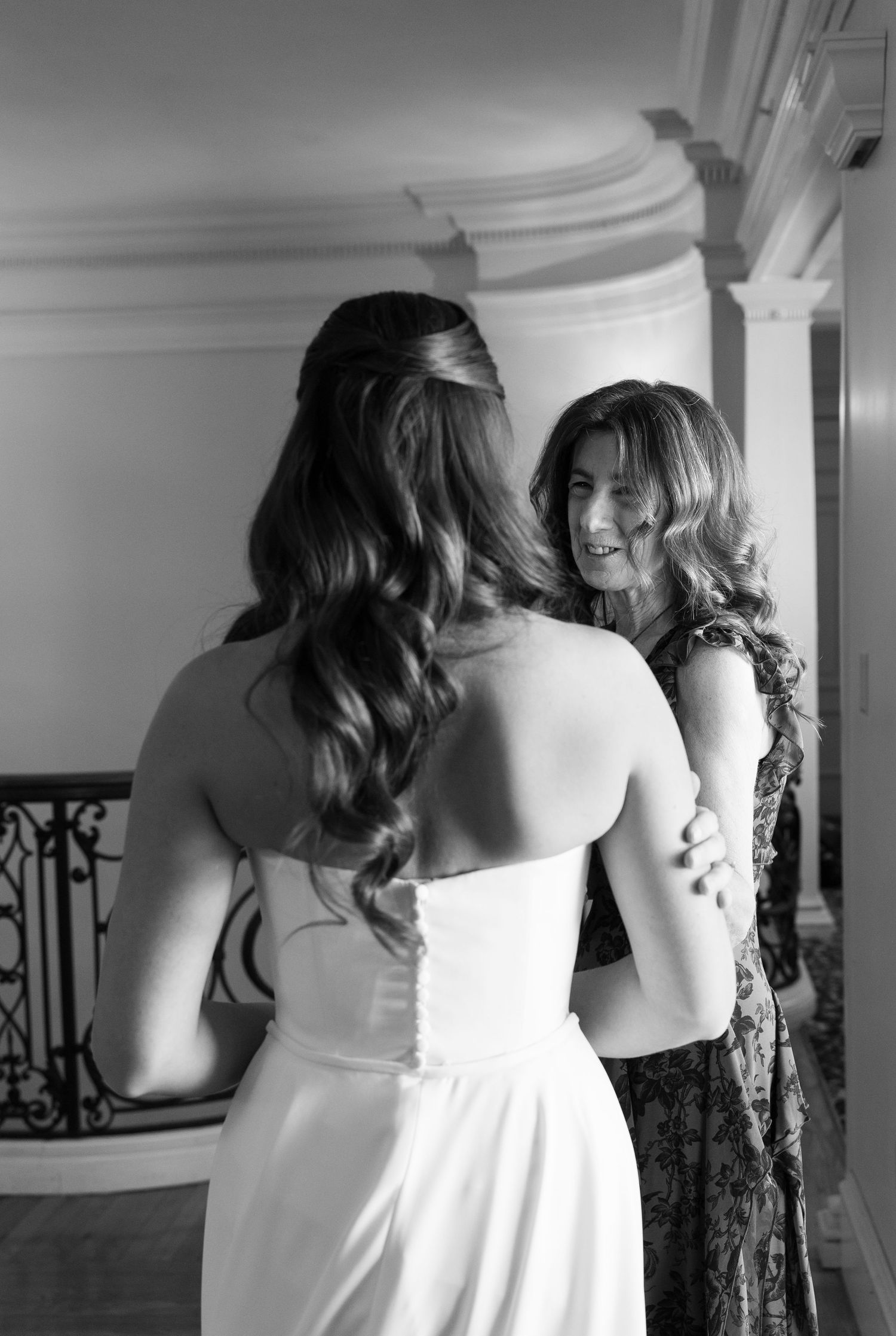 Black and white photo of two women in formal wear sharing a joyful moment.