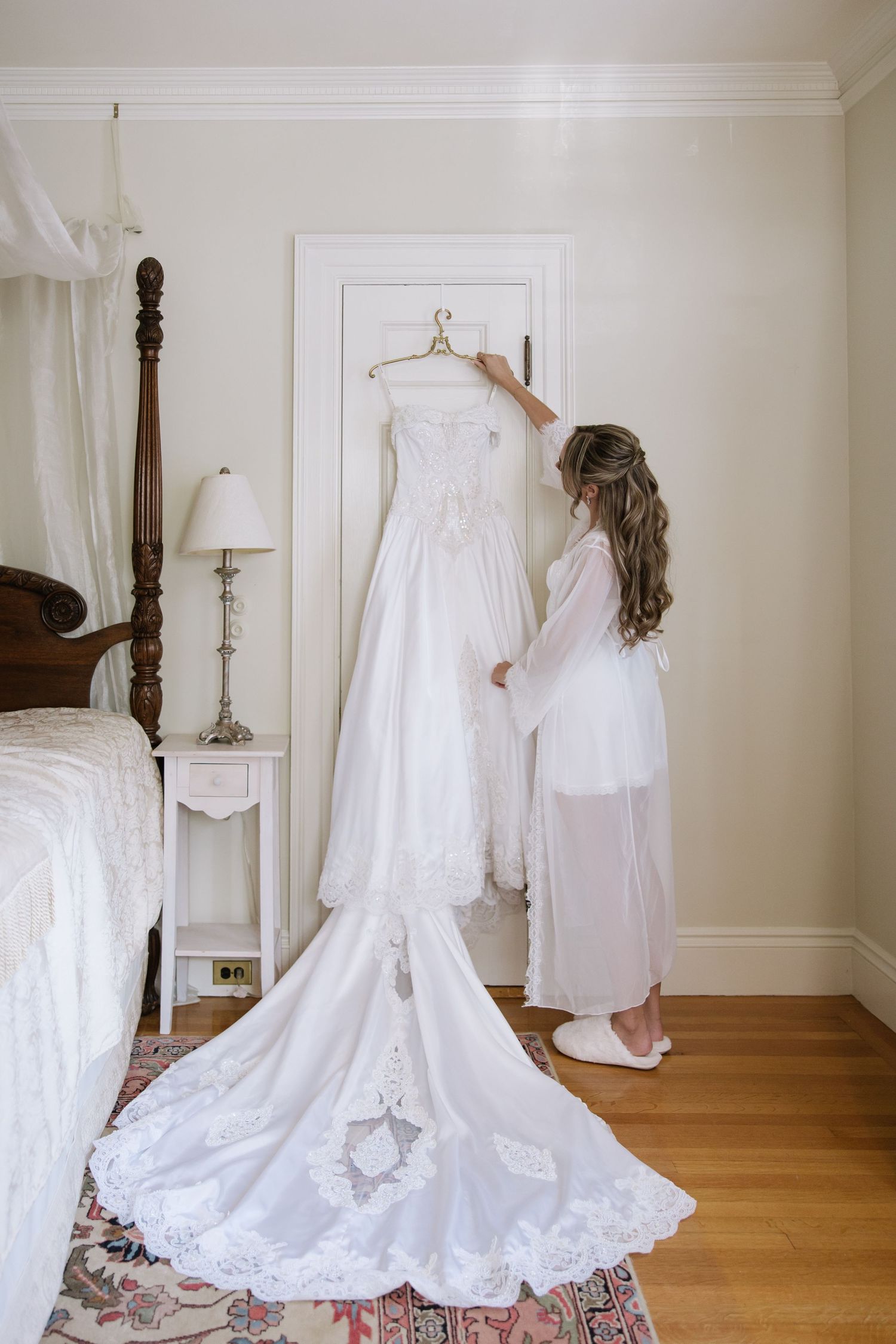 Collection of vintage white wedding dresses displayed on hangers in an elegant room.