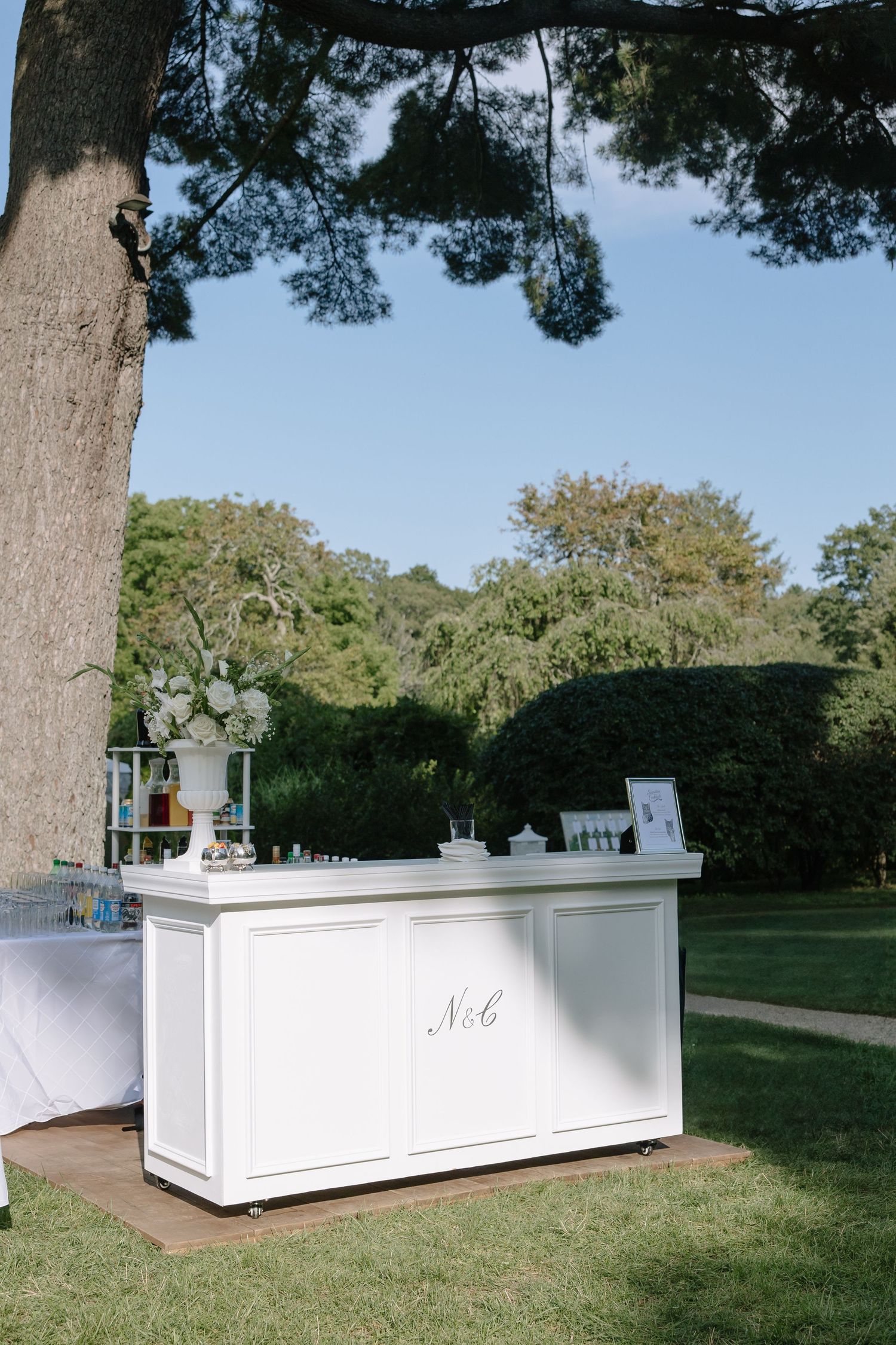White outdoor bar stations set up on grass for an elegant garden wedding reception.