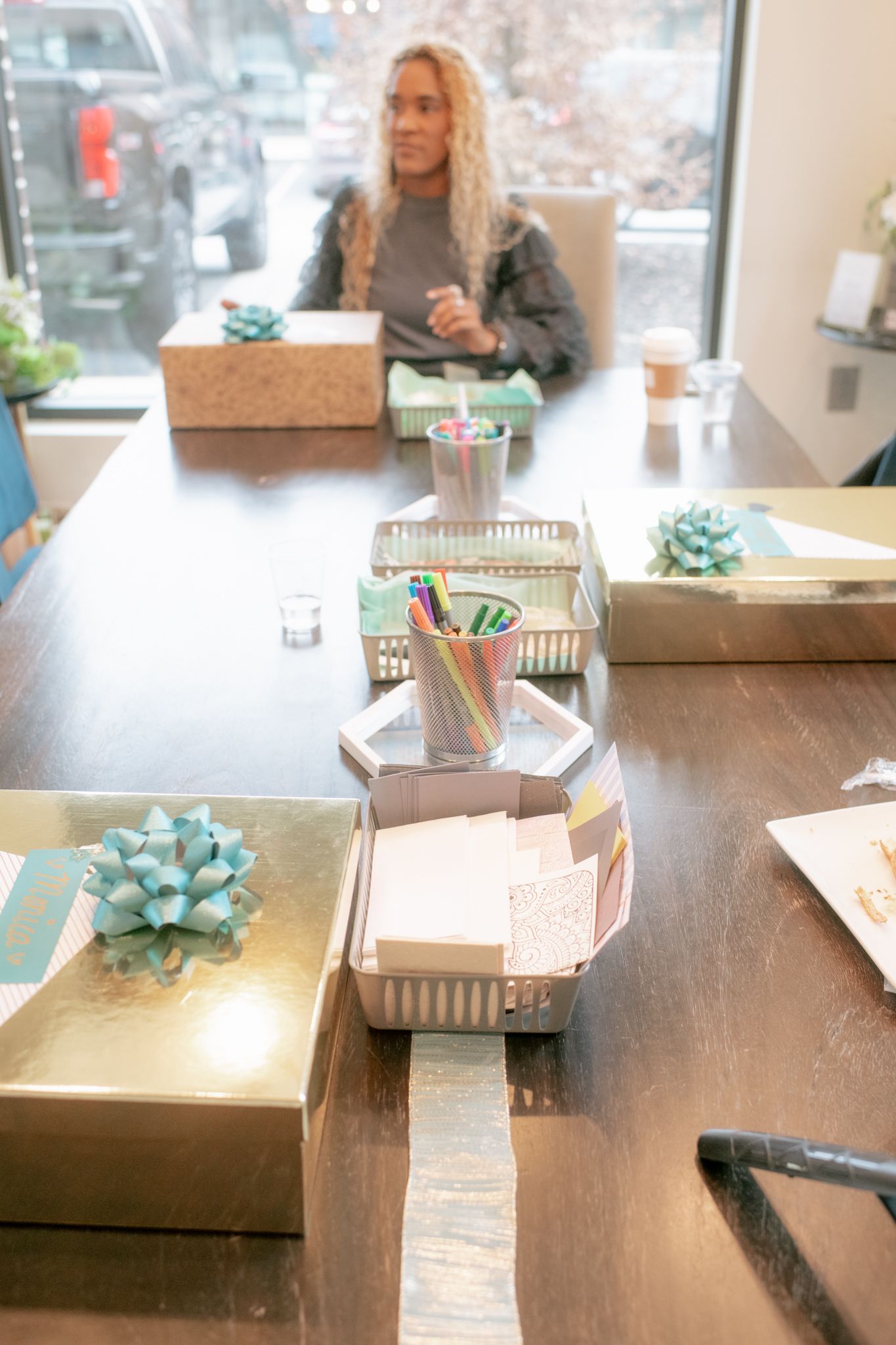A wooden table setup with decorative boxes and teal accents in a bright modern space.