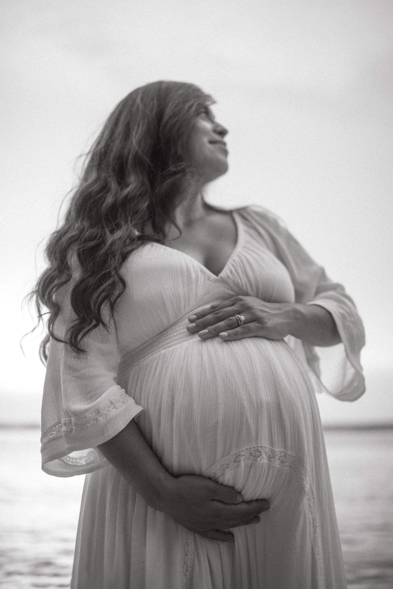 A series of ethereal black and white photos showing embracing silhouettes in white dresses against a misty ocean backdrop.