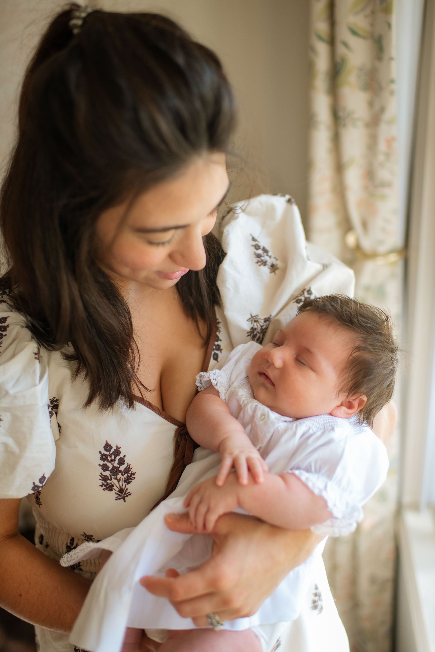 A tender moment captured between caregiver and infant in natural window light.