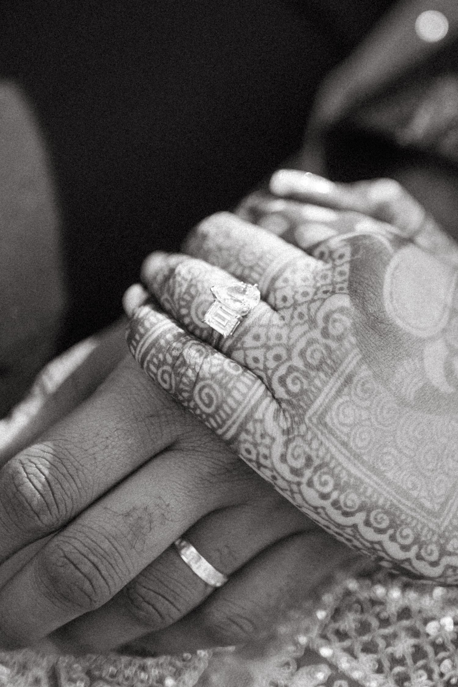 A close-up black and white photo shows a baby sleeping peacefully in detailed patterned bedding.