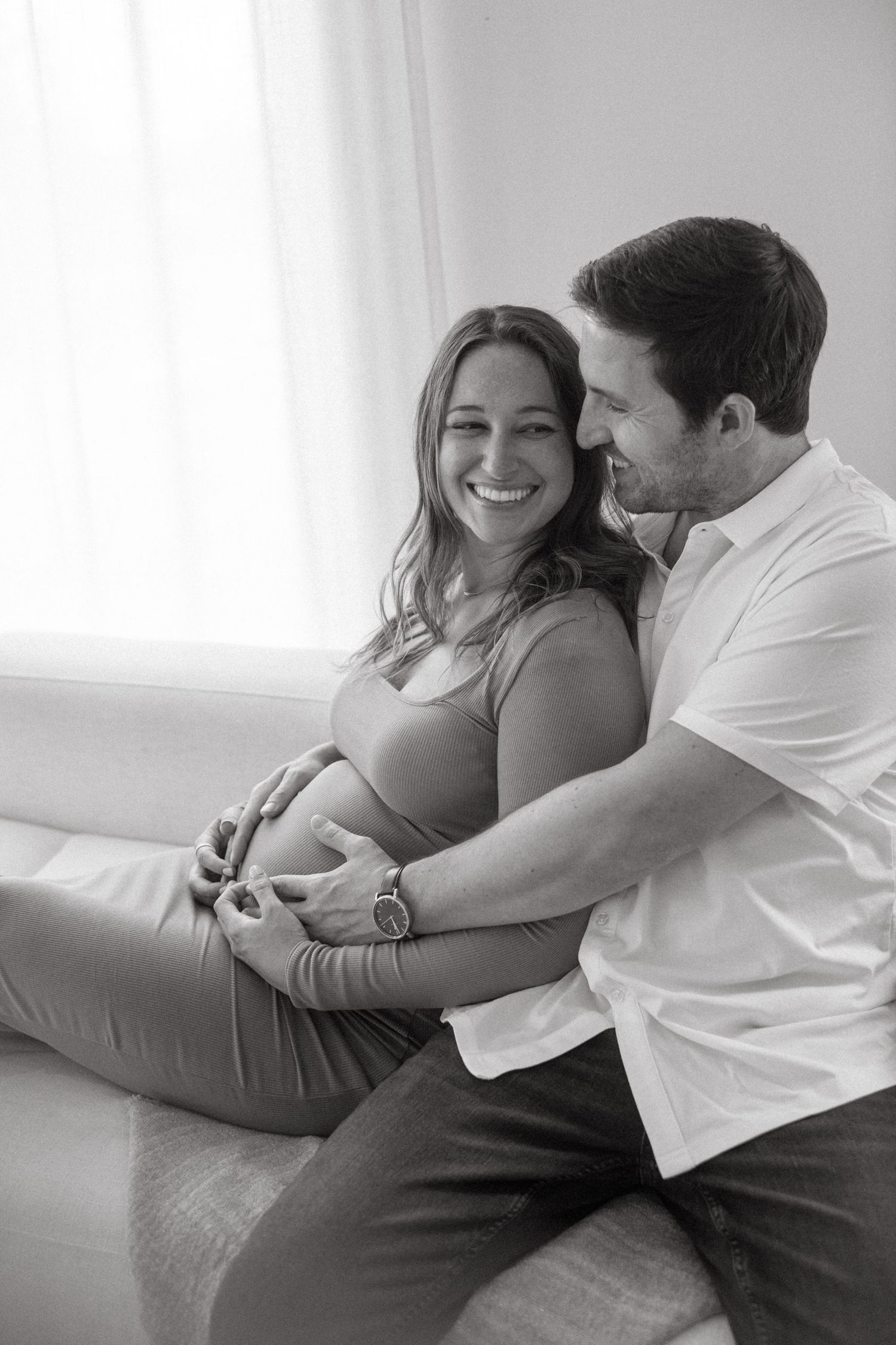 Black and white intimate maternity photo of couple sharing tender moment.