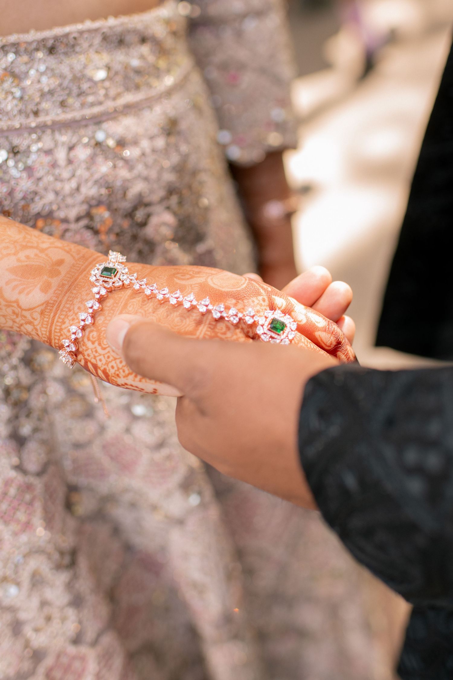 Delicate henna mehndi designs adorned with sparkling rhinestones create an elegant bridal accessory on an arm.