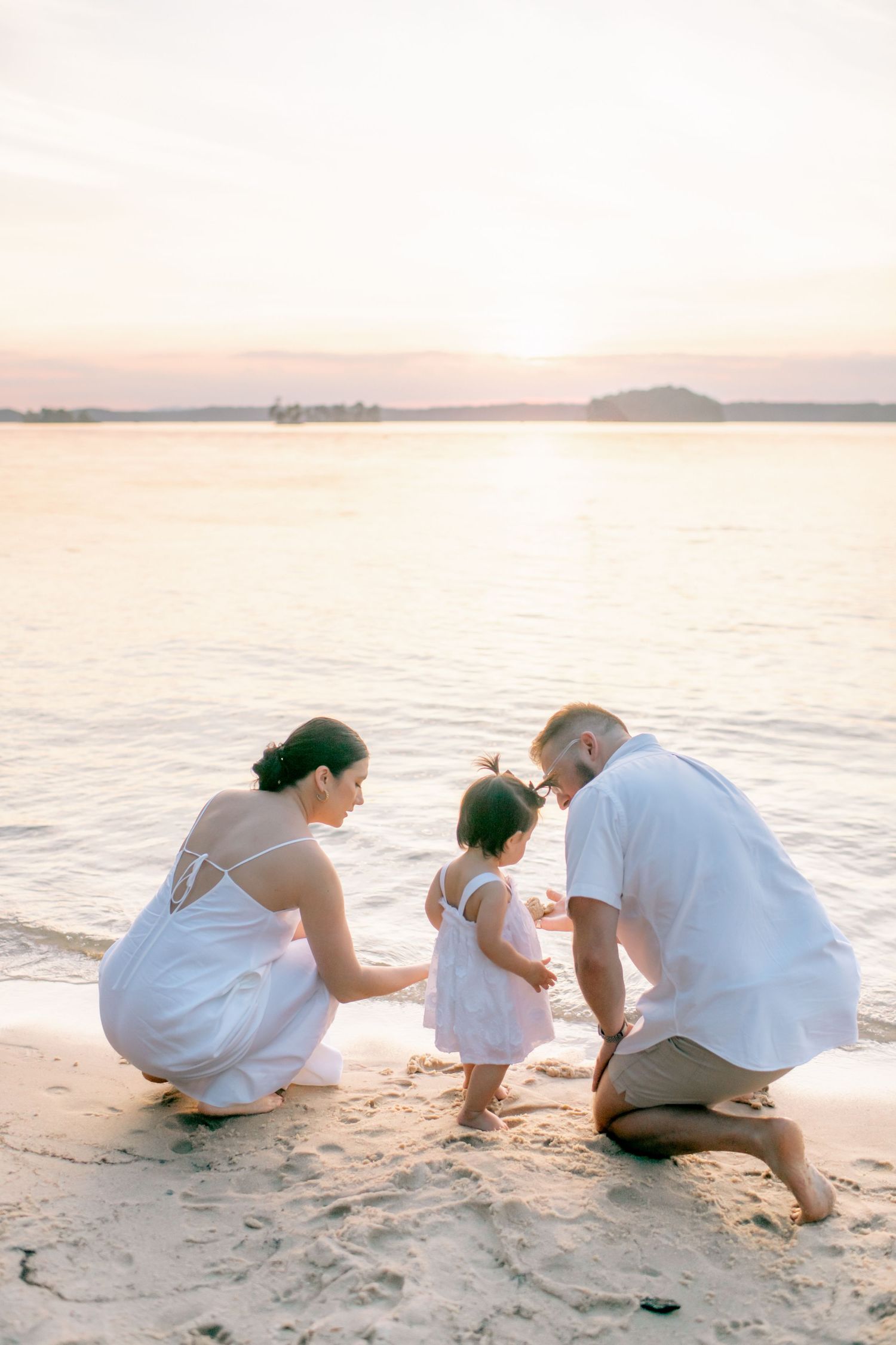 Family explores the sandy shoreline together at sunset.