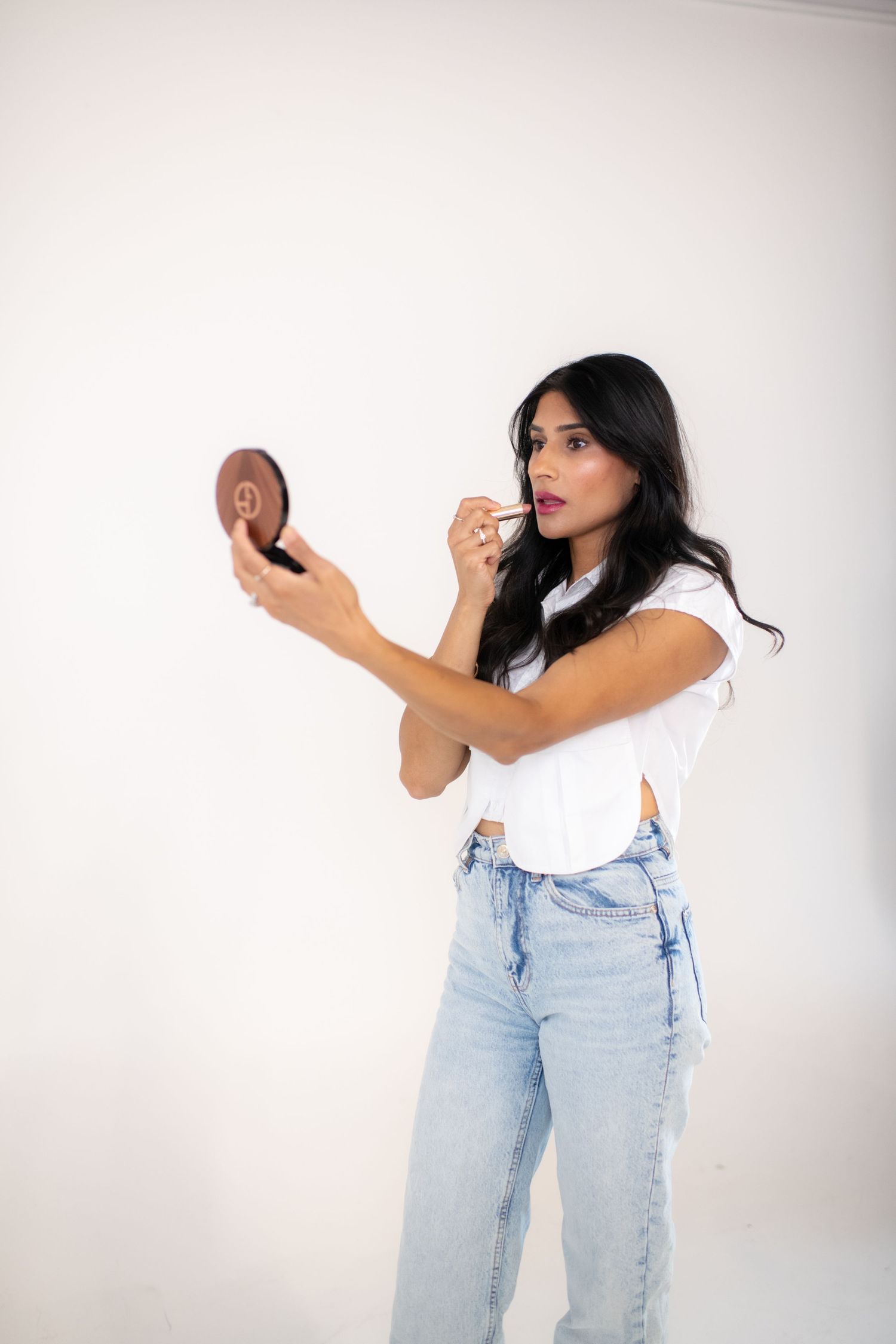 A person in light blue jeans and white top poses dynamically against a white background in a photo series.