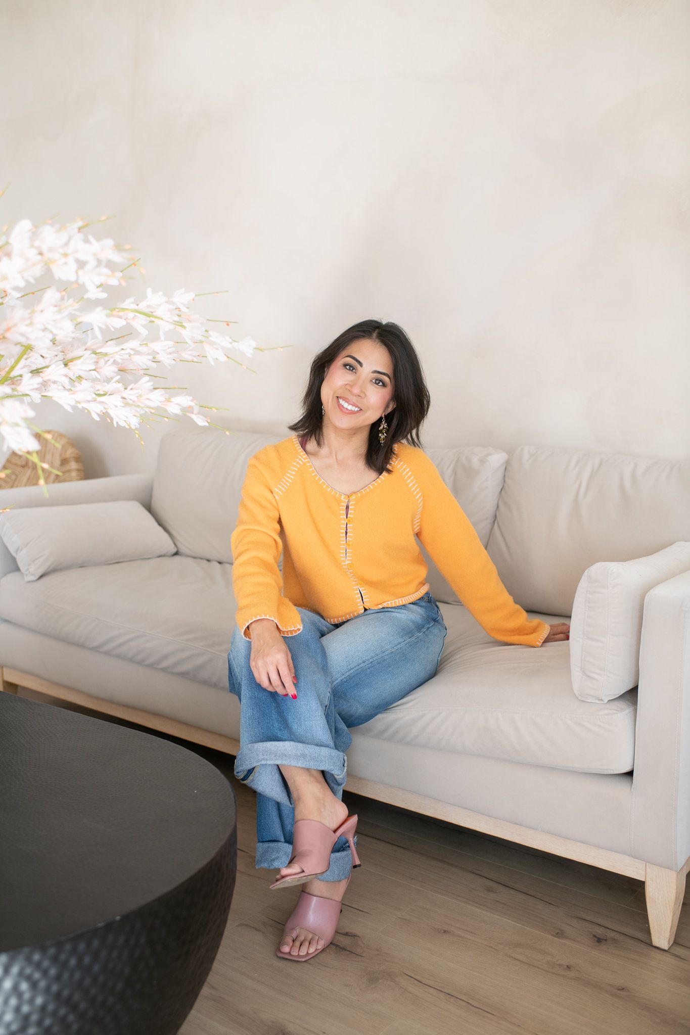 Person relaxing on gray couch wearing yellow top and jeans in minimalist living room.