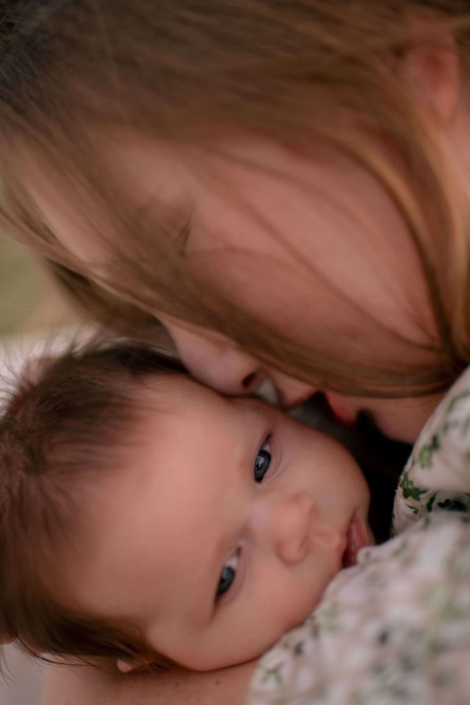 A tender moment captured in soft focus shows a parent and baby sharing an intimate cuddle.