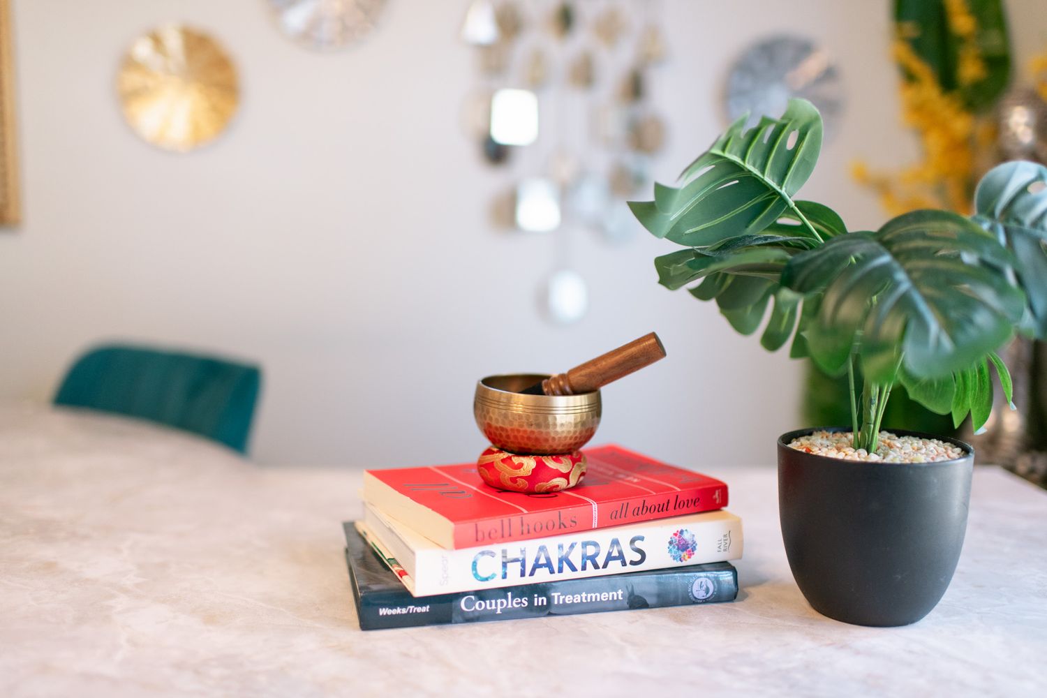 Books about chakras and spiritual topics arranged with plants and decor on a white surface.