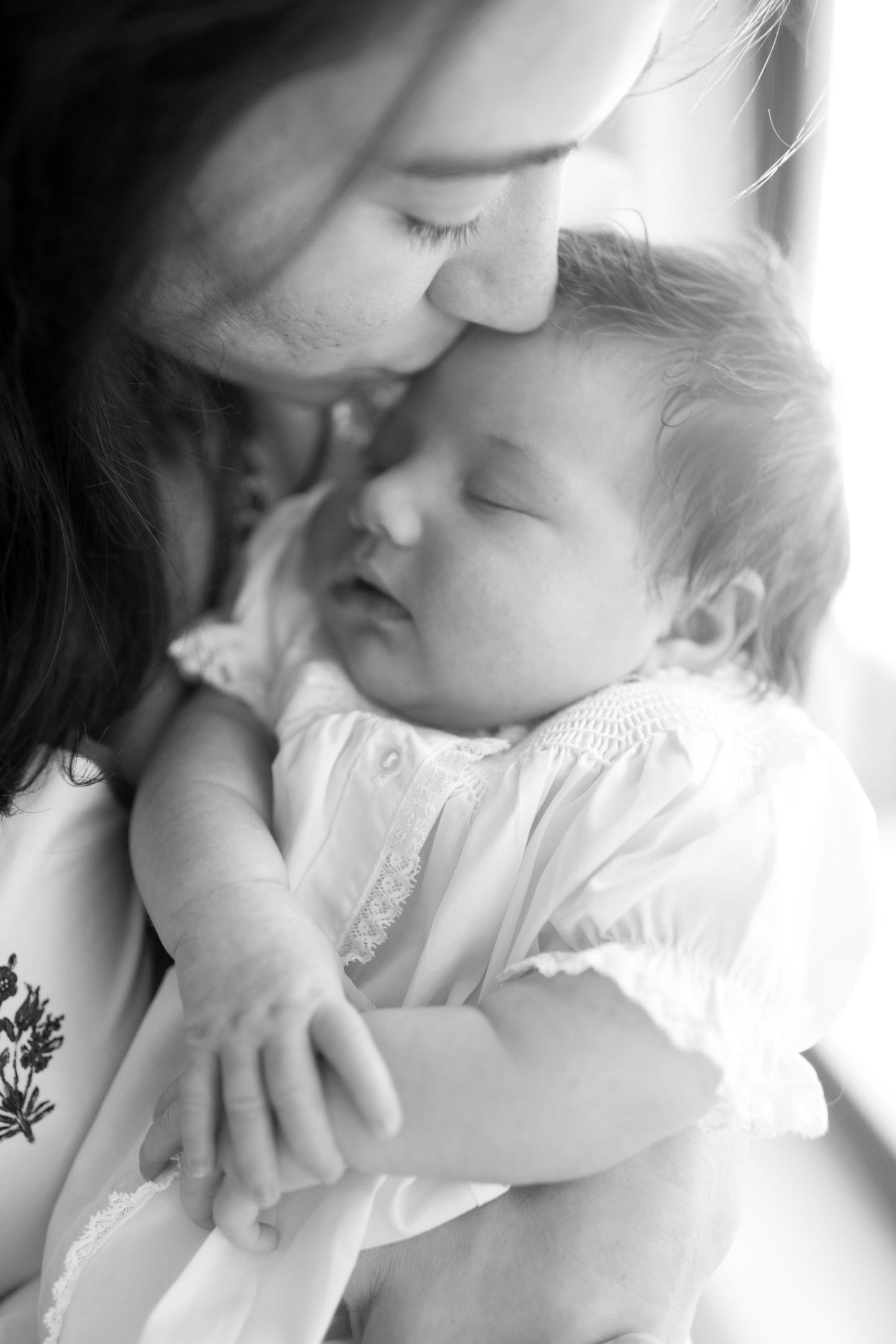 An intimate black and white portrait of a tender moment with a sleeping infant.