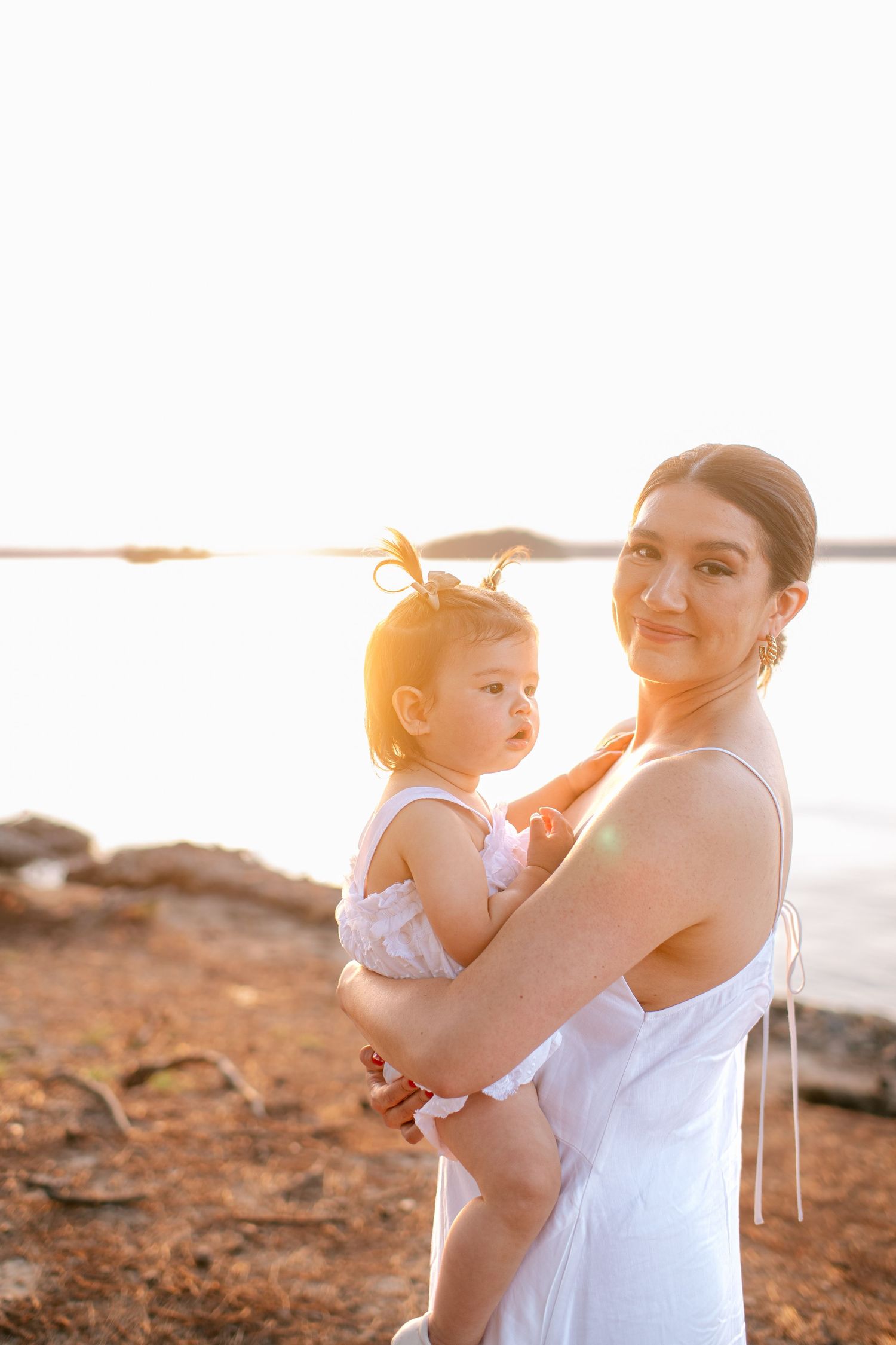 Parent and child sharing tender moments on a beach during golden hour.