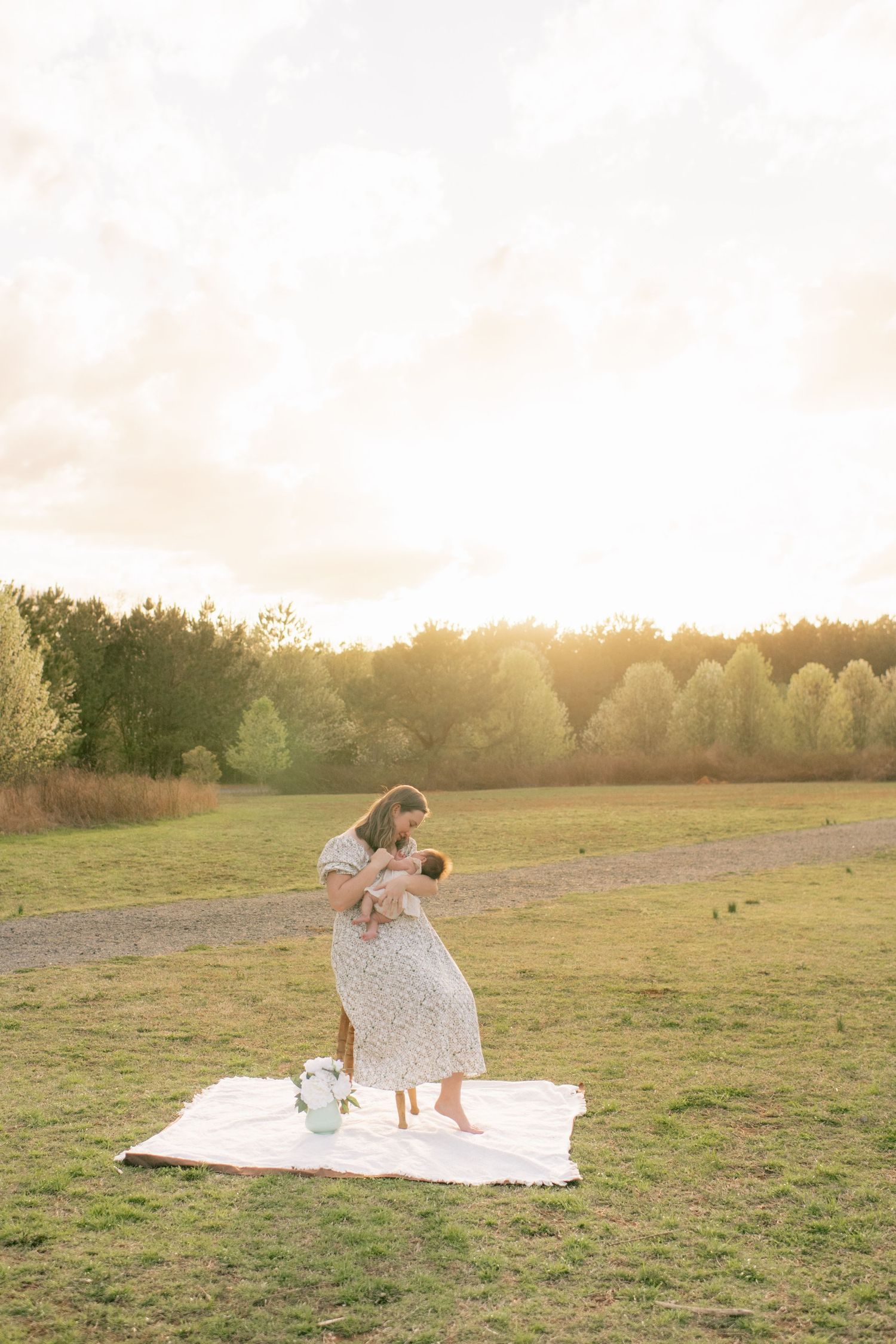 Two figures dance together on a white blanket in a sunny meadow at sunset as golden light streams across the field.