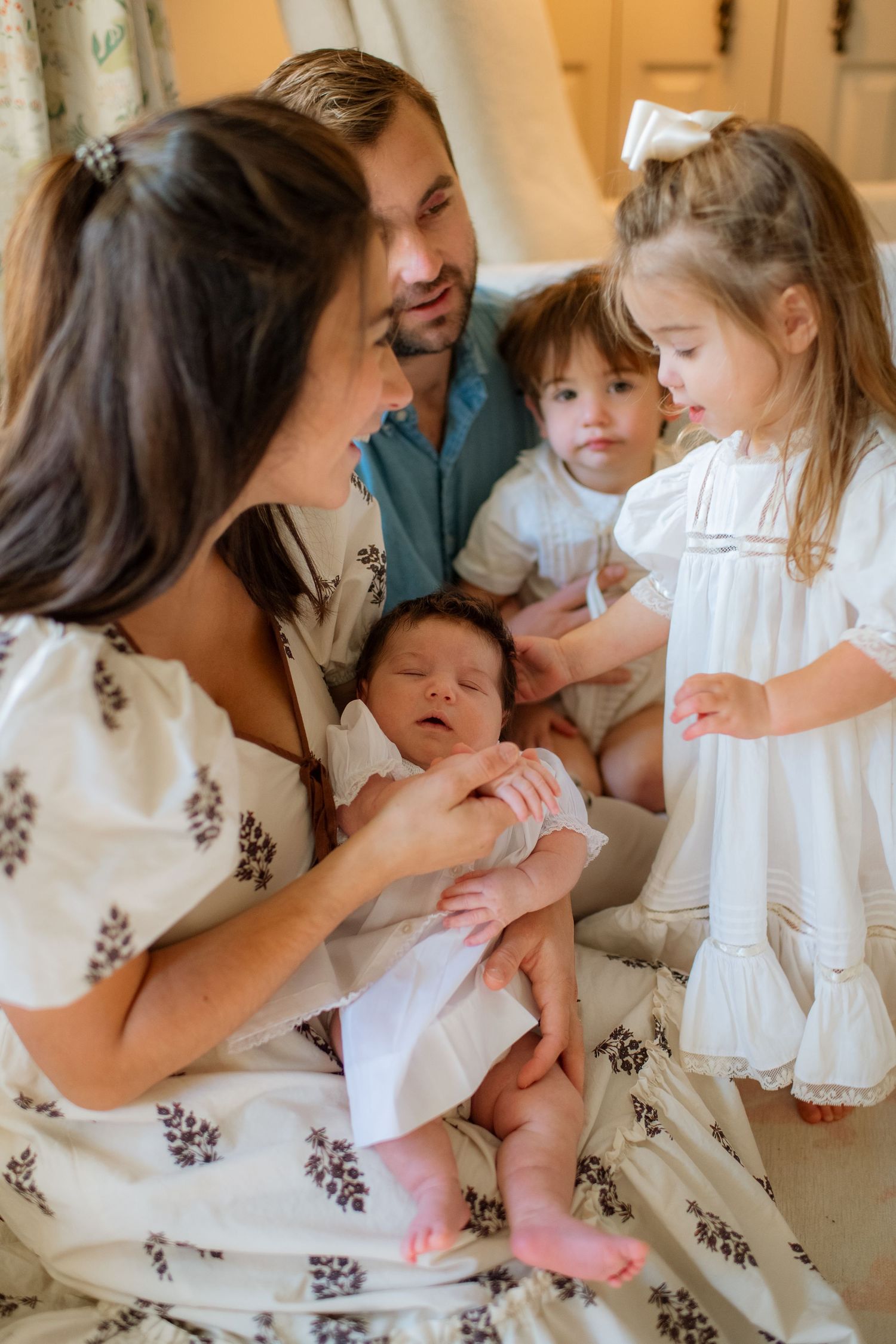 A family sharing loving moments together on a couch, dressed in coordinating white outfits.