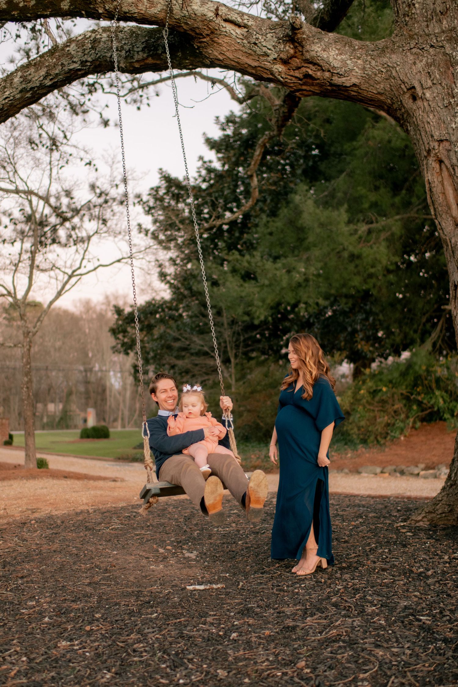 Family enjoying time together at a tree swing in a park during golden hour.