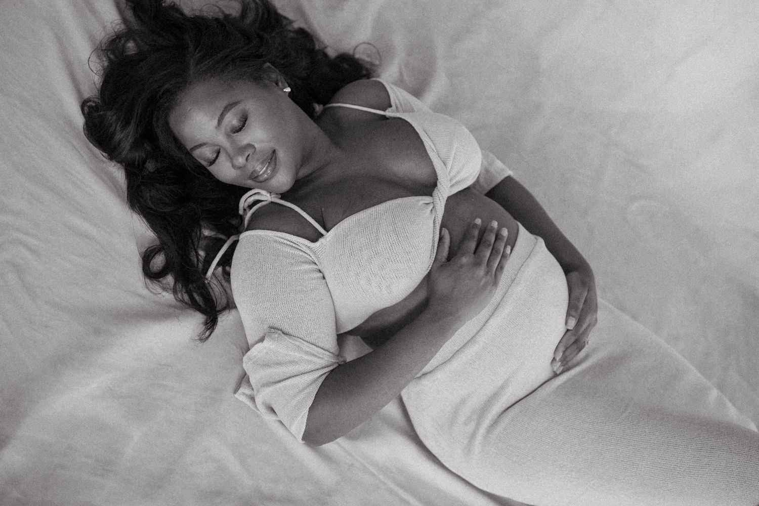 Black and white artistic maternity photo with soft fabric backdrop.