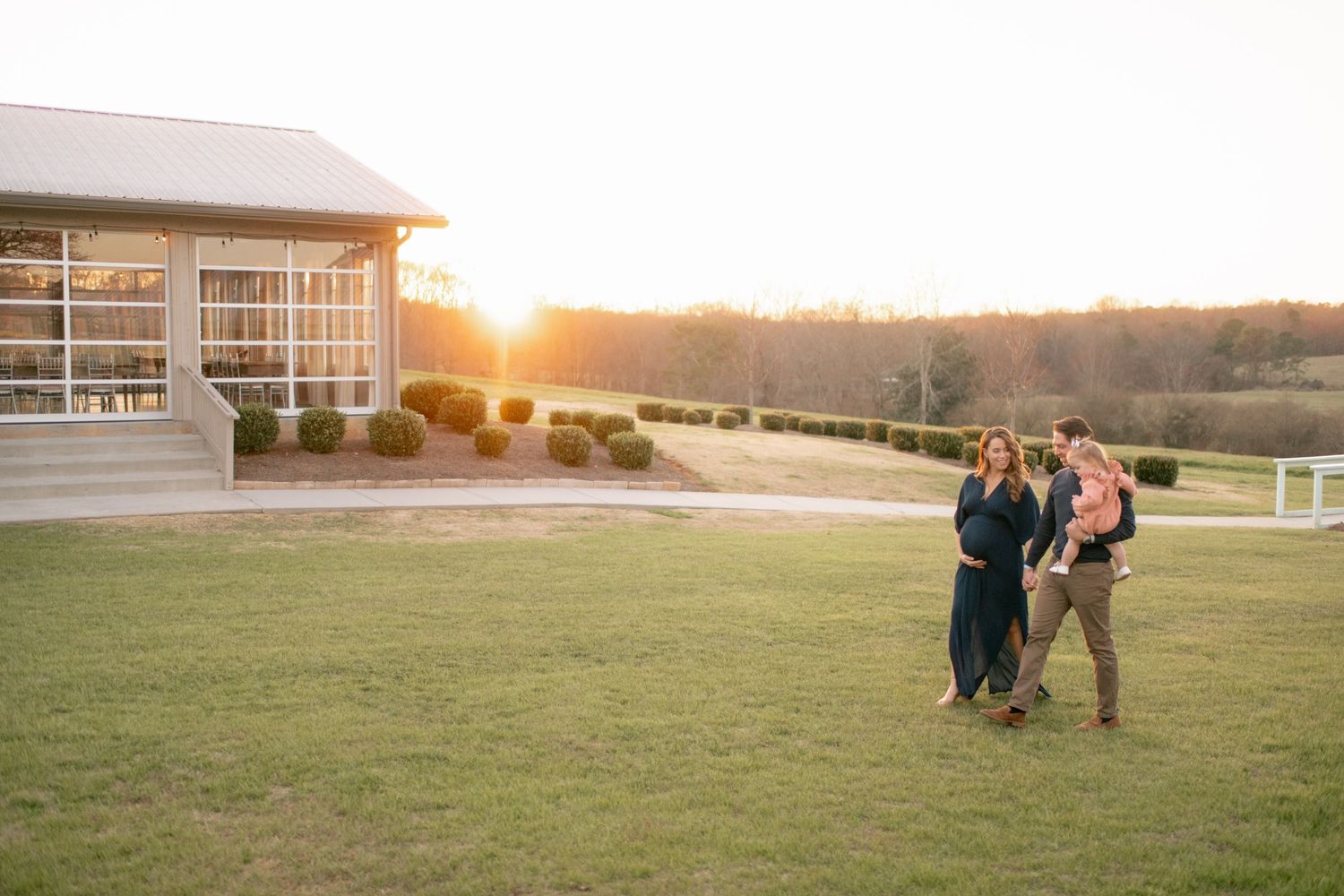 A stunning sunset view at a modern venue with rolling hills in the background and green lawn in the foreground.