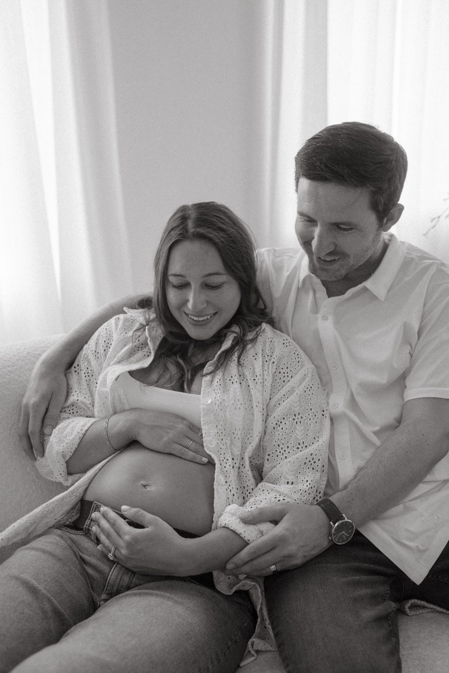 A couple shares tender moments during an indoor maternity photoshoot.