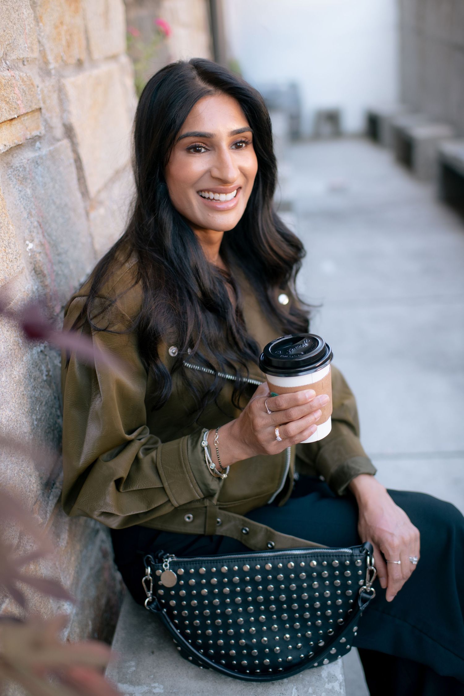 Casual lifestyle portrait series showing someone in an olive jacket holding coffee against a brick wall background.