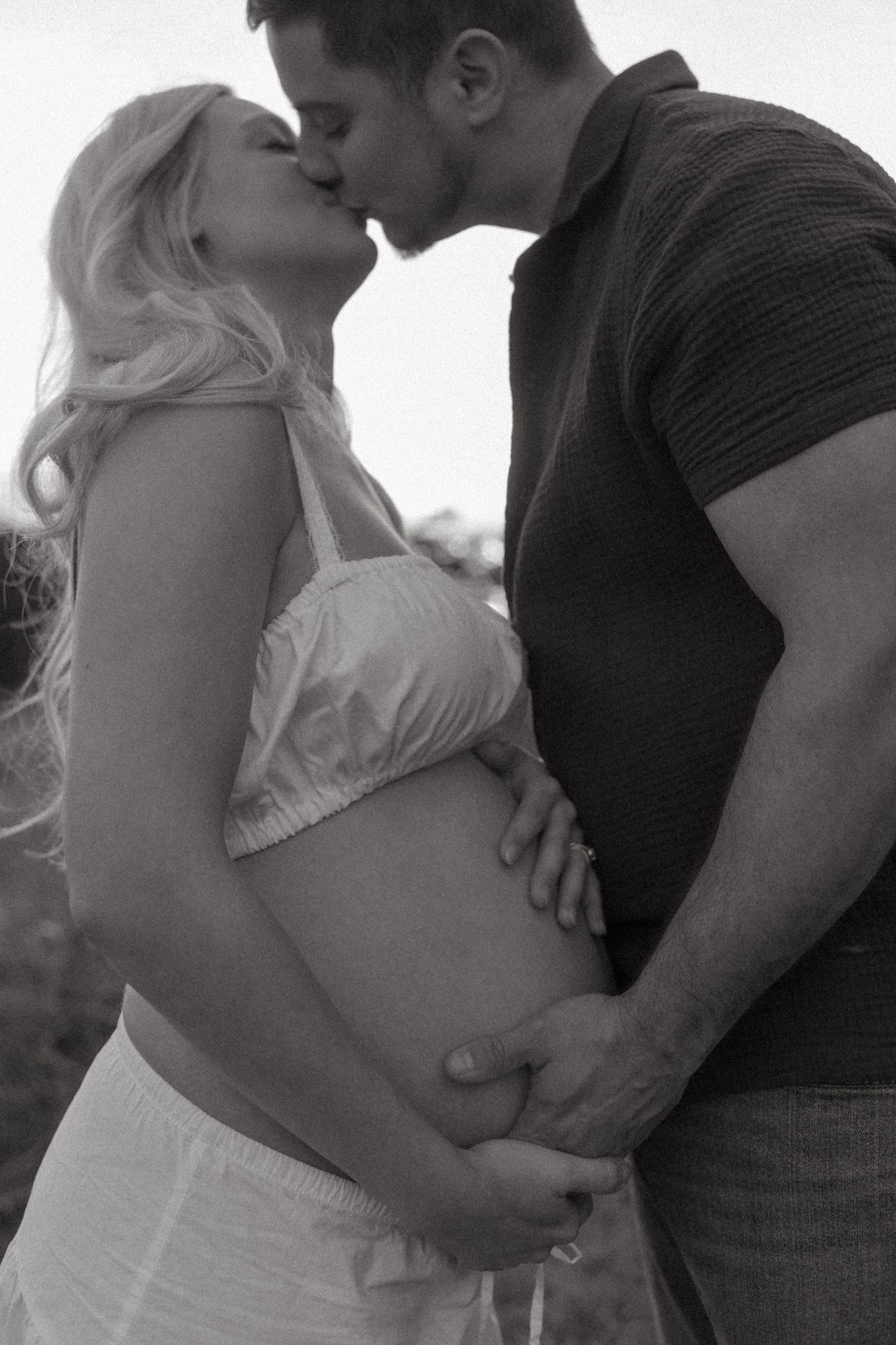 Black and white maternity photos showing tender moments between an expectant couple.
