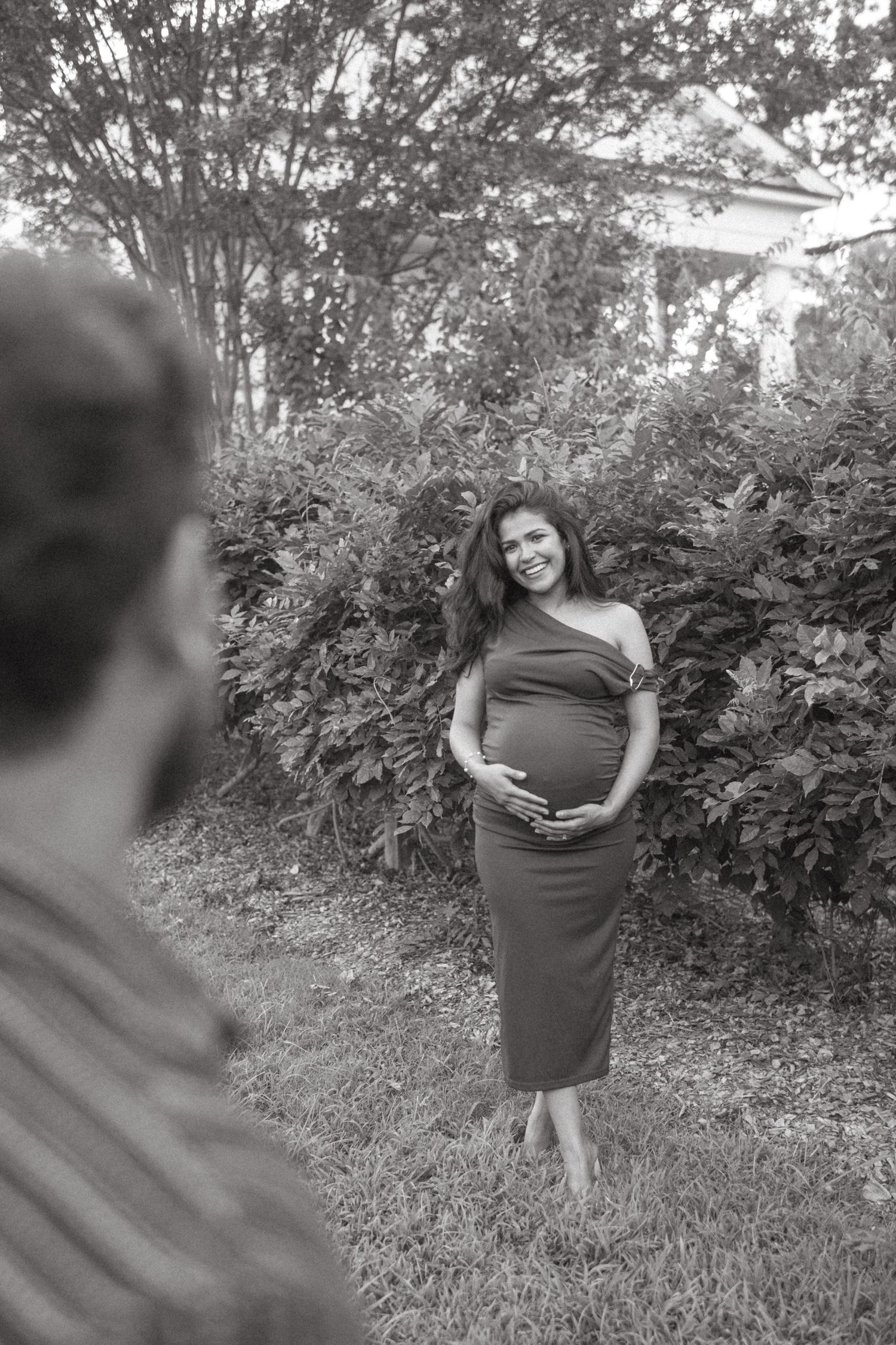 Black and white maternity portraits taken in a natural outdoor setting.