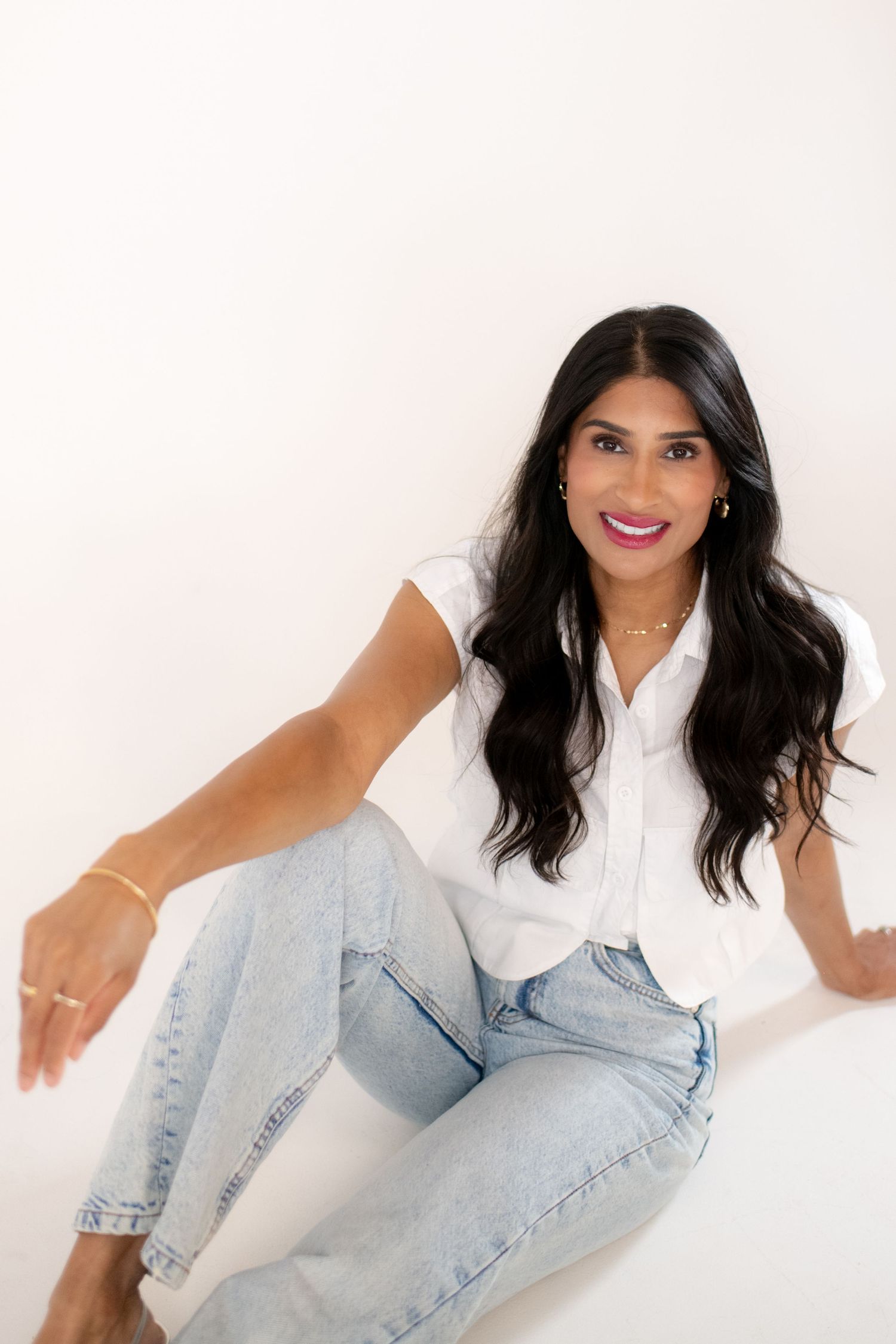 Person in casual white shirt and light denim strikes dynamic poses against white studio backdrop.