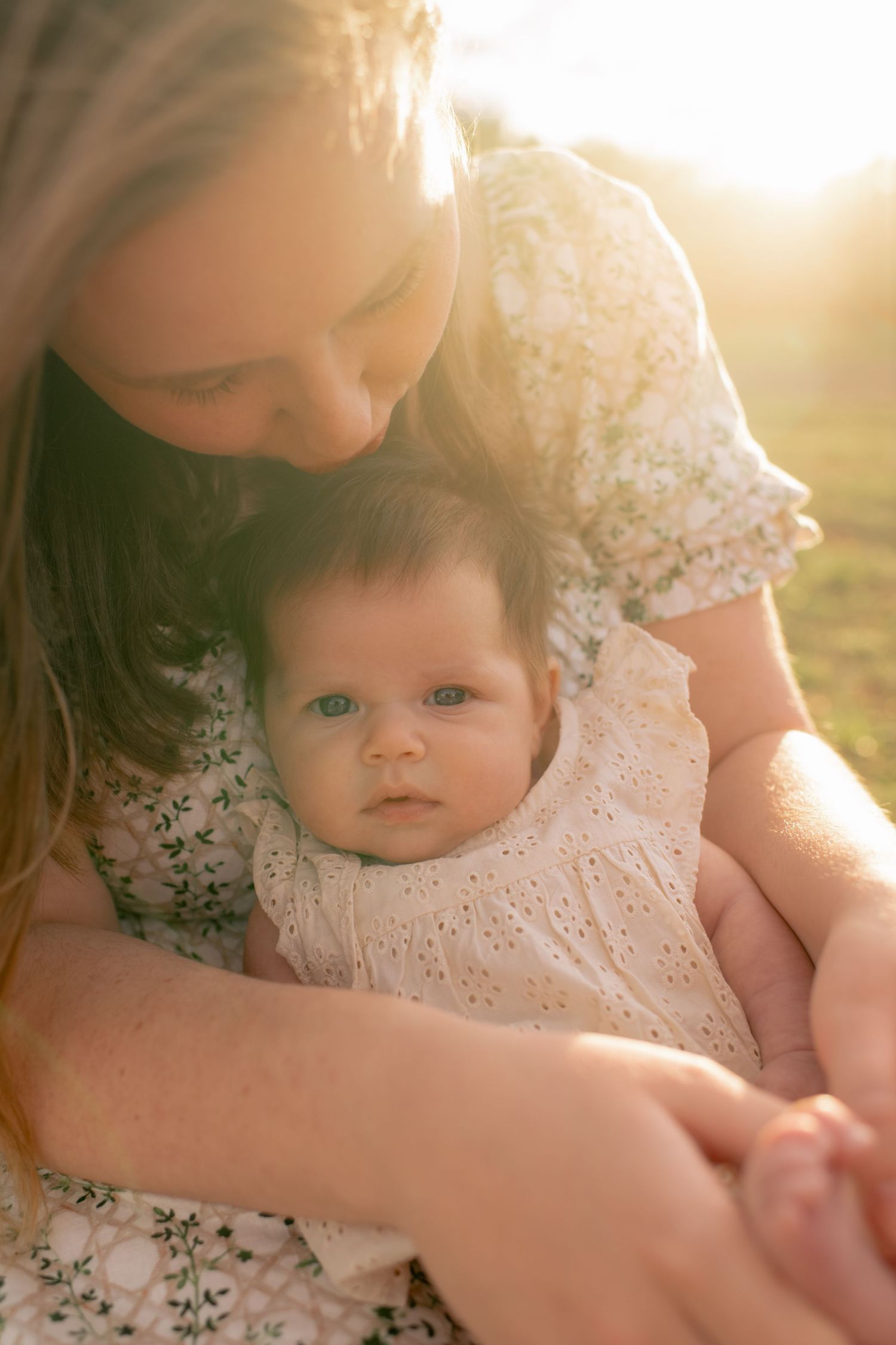 Intimate moment captured in golden sunlight showing tender embrace in floral and eyelet lace dresses.
