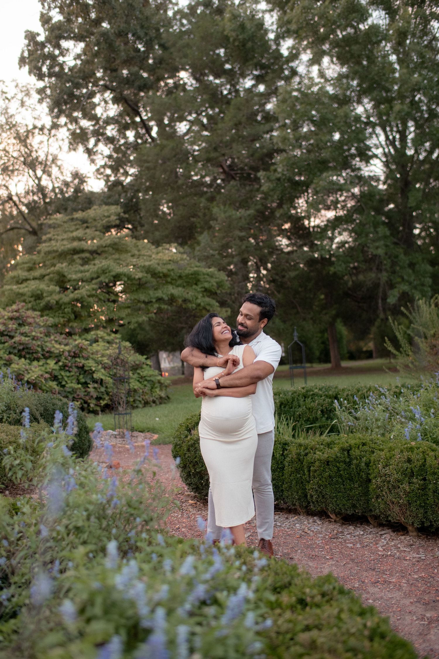 Sweet couple sharing tender moments in garden with purple flowers.