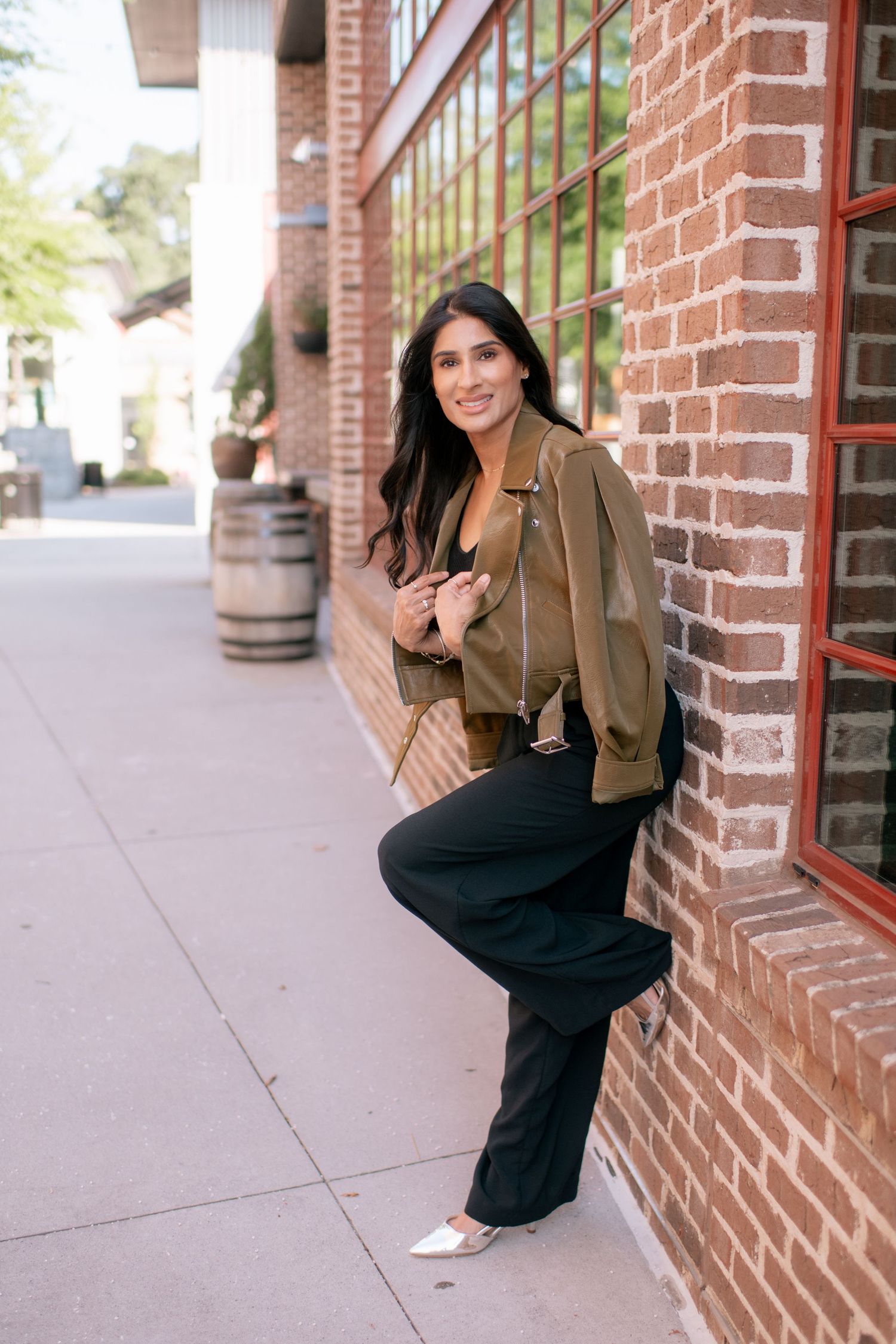 A series of candid poses showing someone in a brown jacket and black pants leaning against a brick wall outdoors.