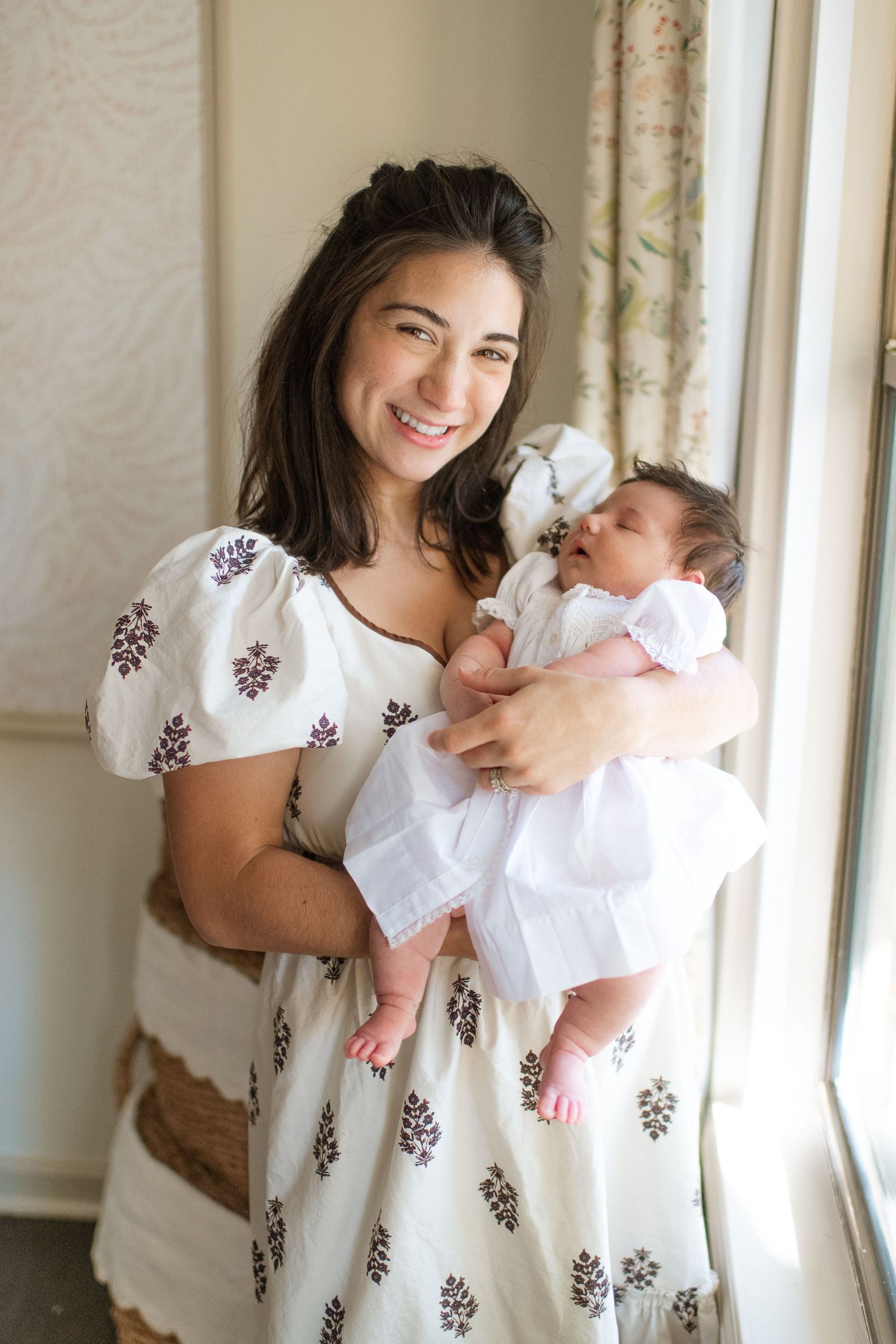 Sweet candid moments between mother and baby in a sunlit room wearing coordinating white outfits.
