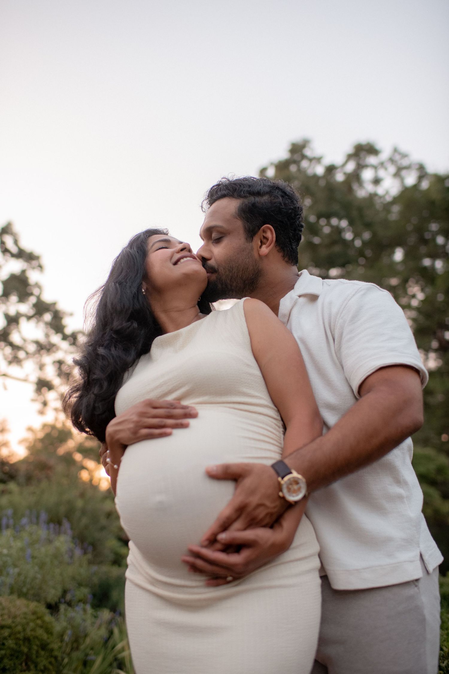 Intimate maternity photos showing loving couple embracing outdoors.