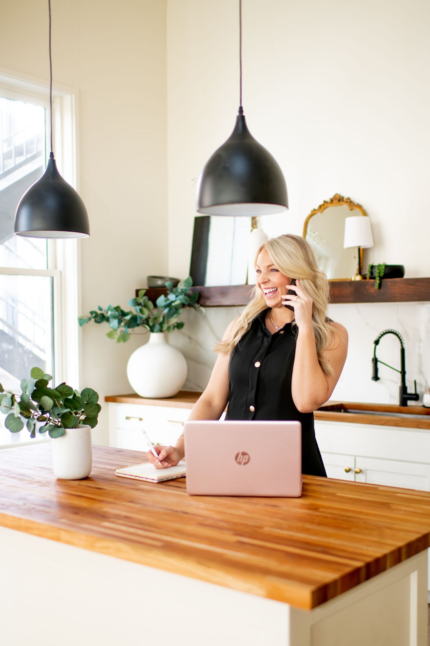 Modern home office setup with wooden table and black pendant lighting fixtures.