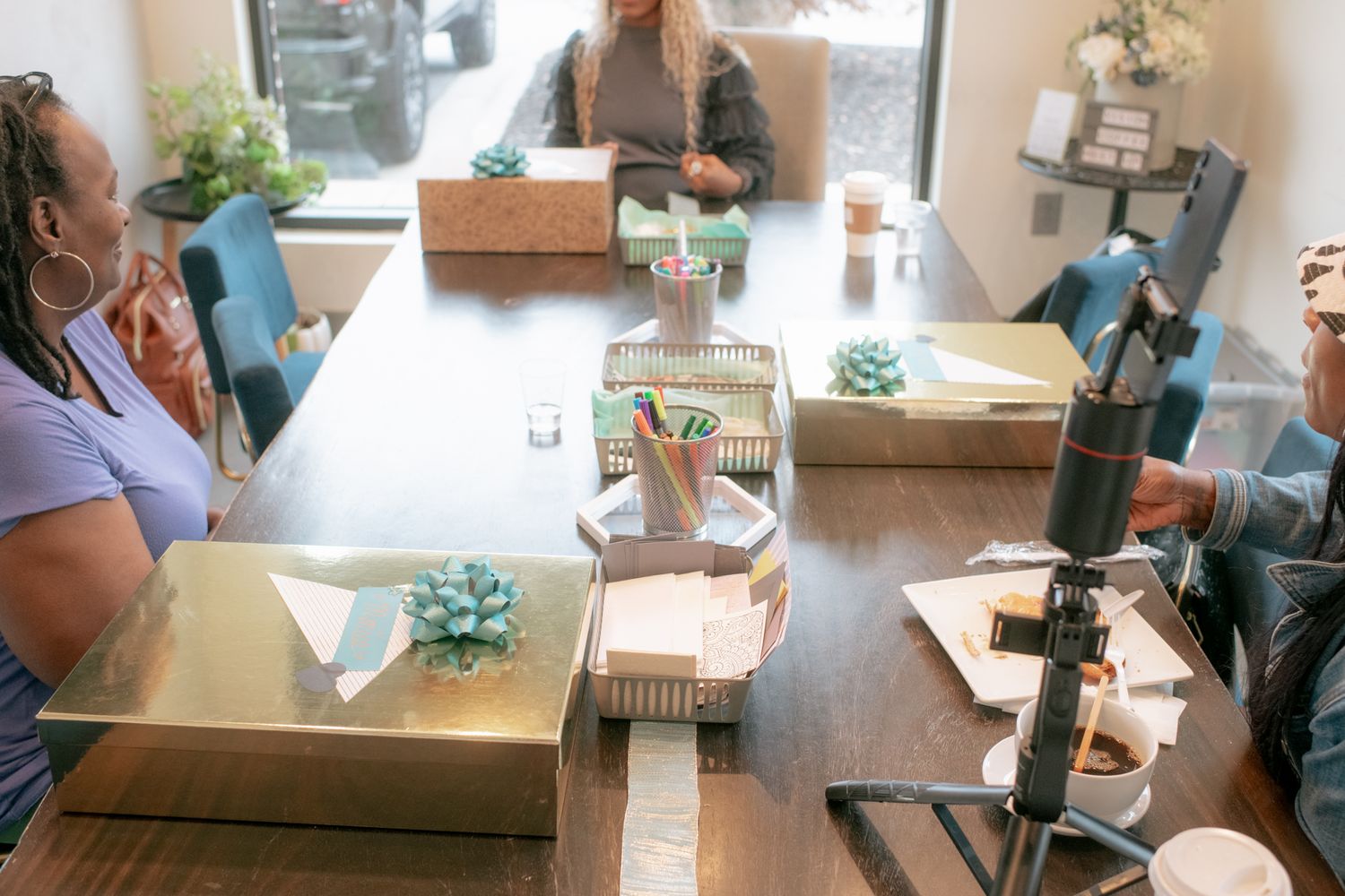Several people sit at tables in a modern office space looking at documents and materials.