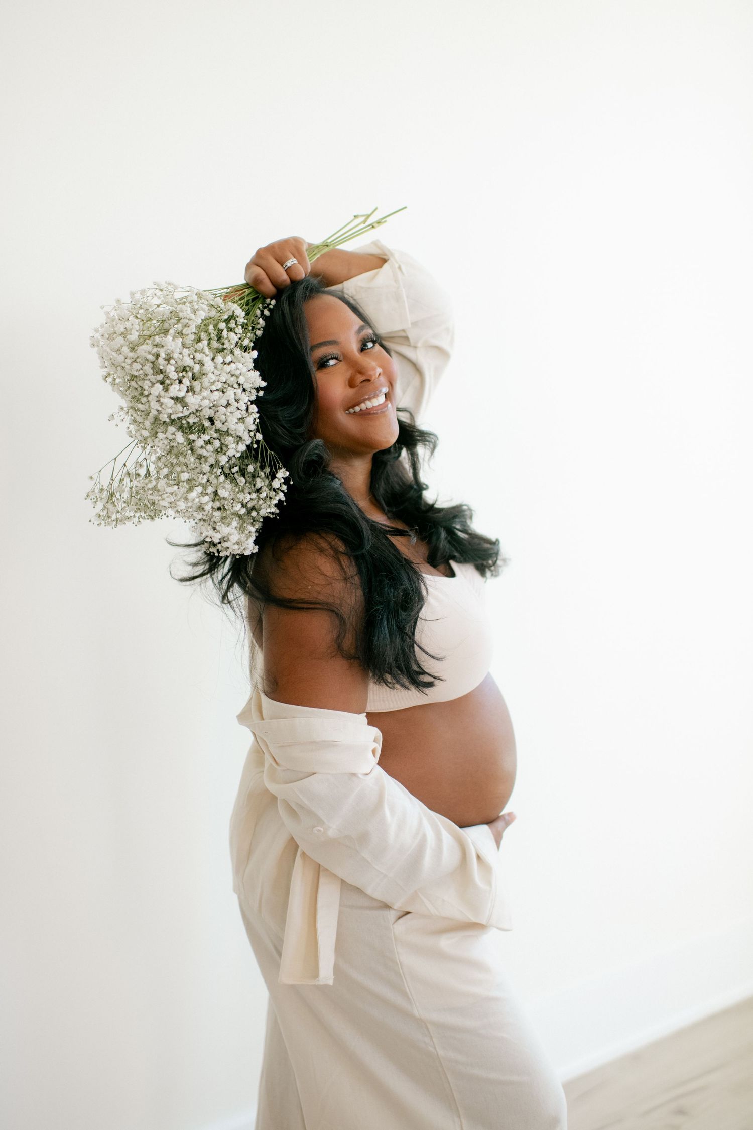 Dreamy maternity photos featuring baby's breath flowers and off-shoulder white dress.