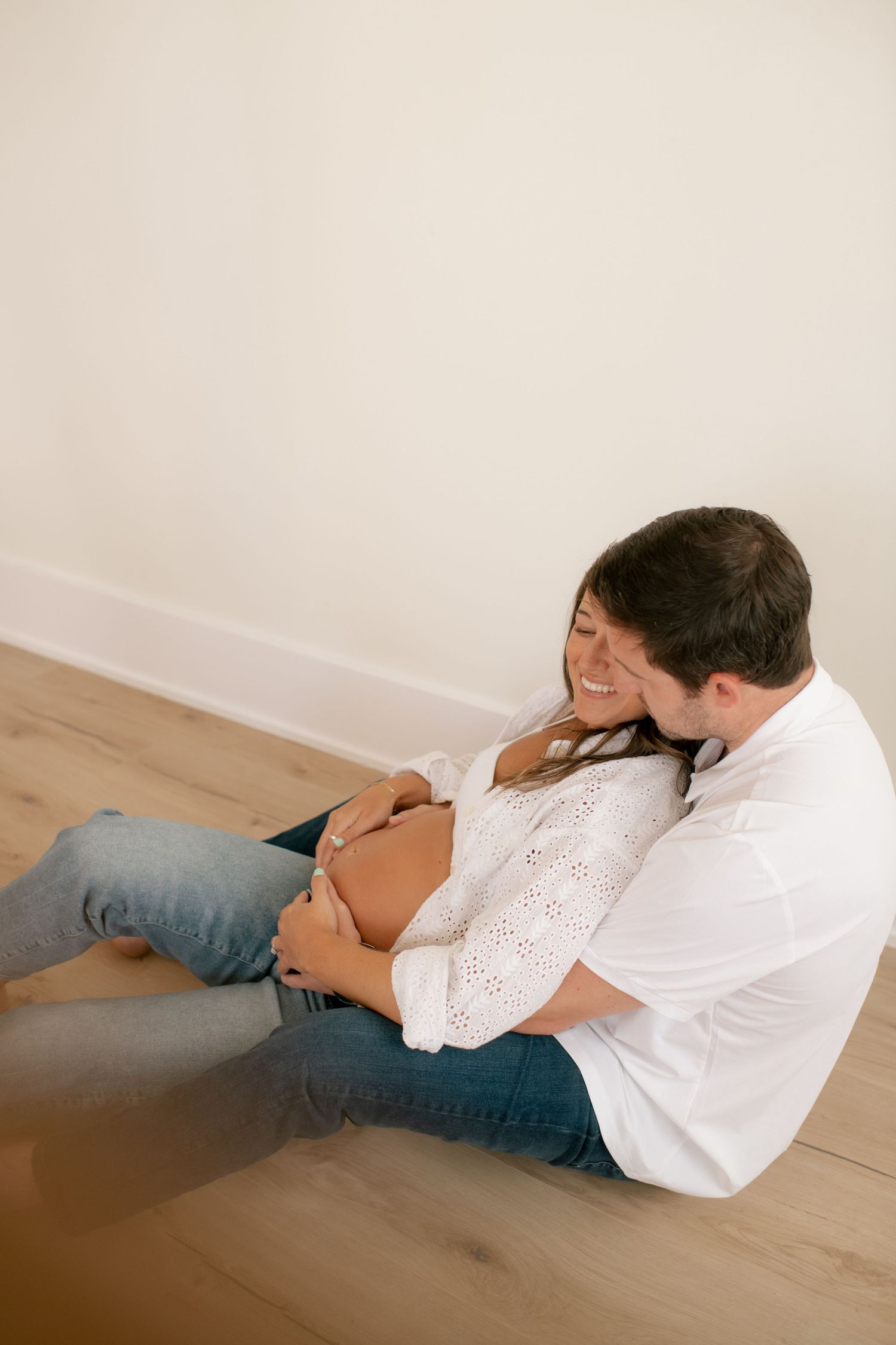 Intimate maternity photos of a couple lying together on a wooden floor.