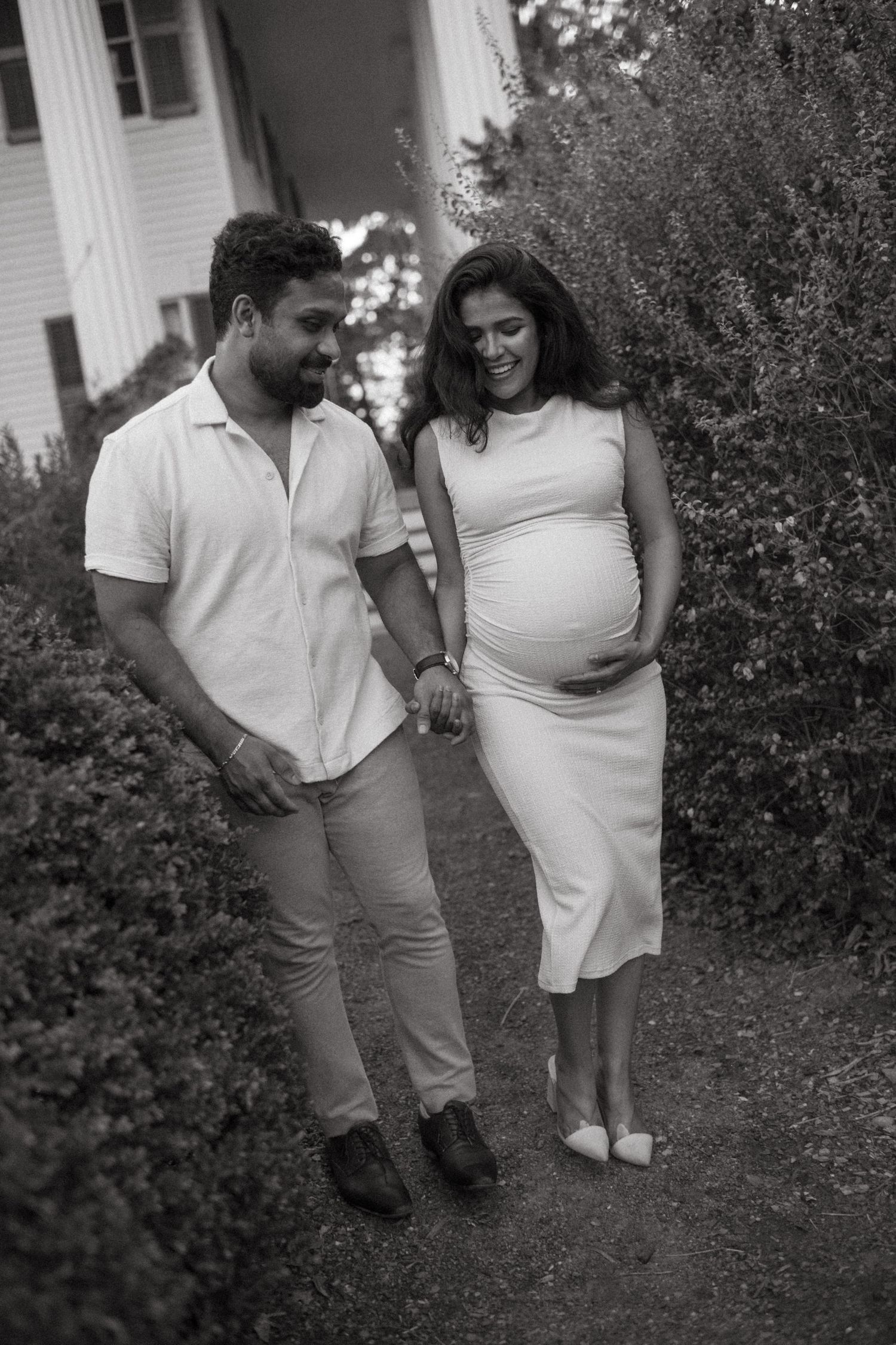 Couple sharing intimate laughs during outdoor maternity photo session.