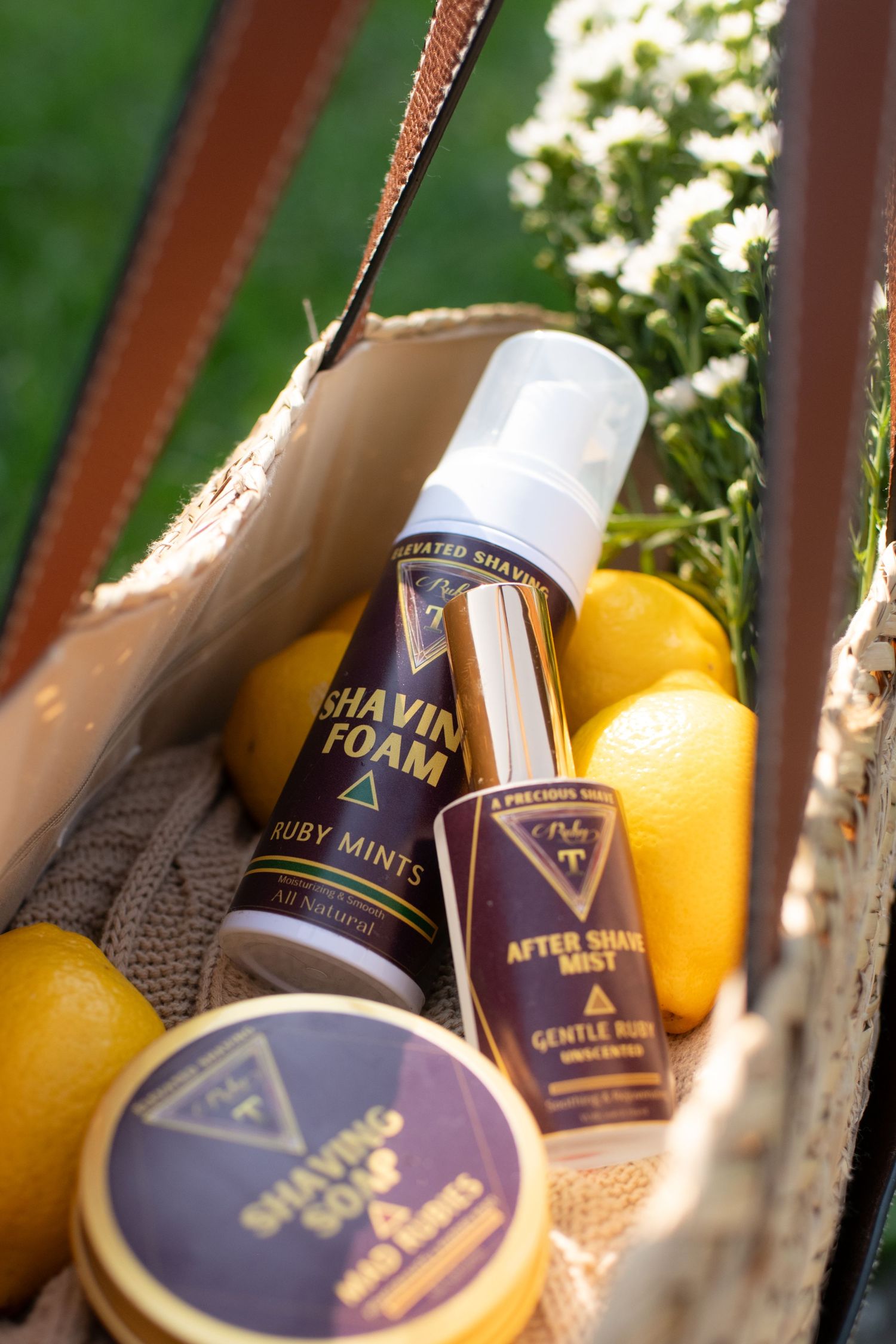 Ruby Mints shaving foam, after shave mist, and shaving soap displayed in a basket with fresh lemons outdoors.