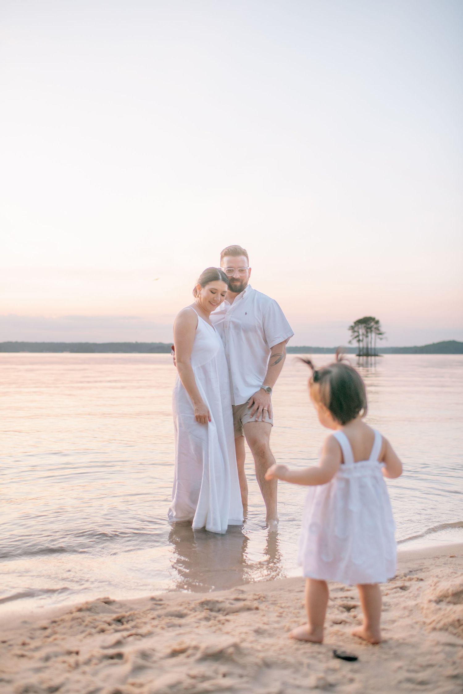 Family shares playful moments along the shoreline during sunset.