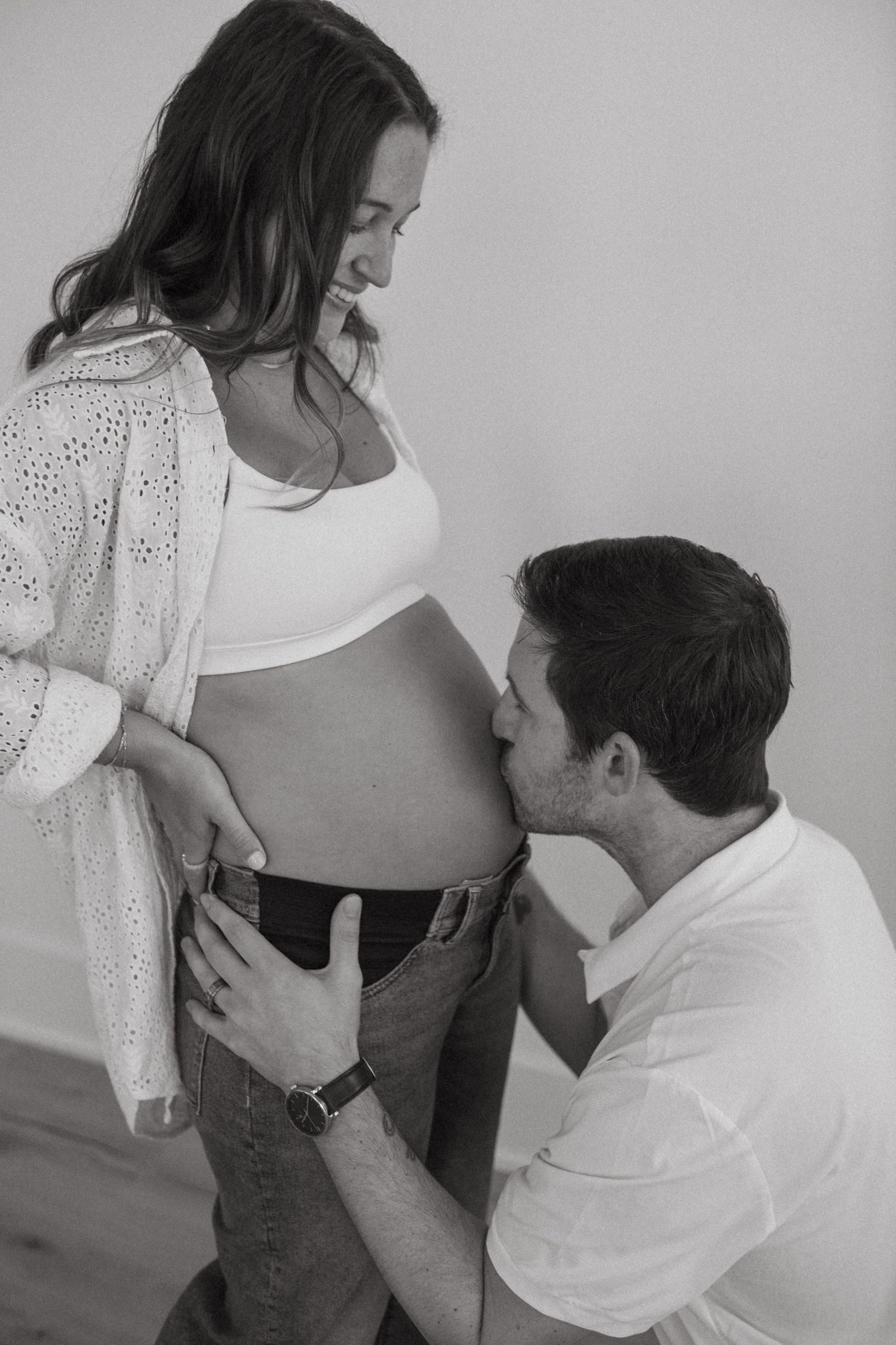 A romantic maternity photoshoot showing tender moments between a couple in black and white.