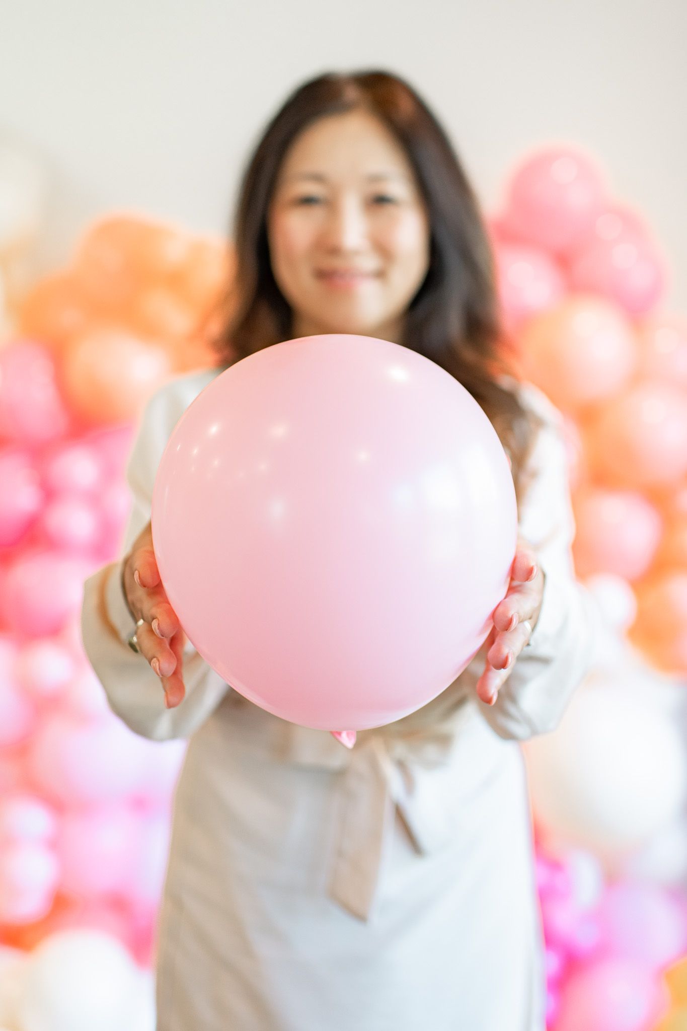 Person in white shirt holds pink balloon against colorful balloon backdrop in progressive sequence.