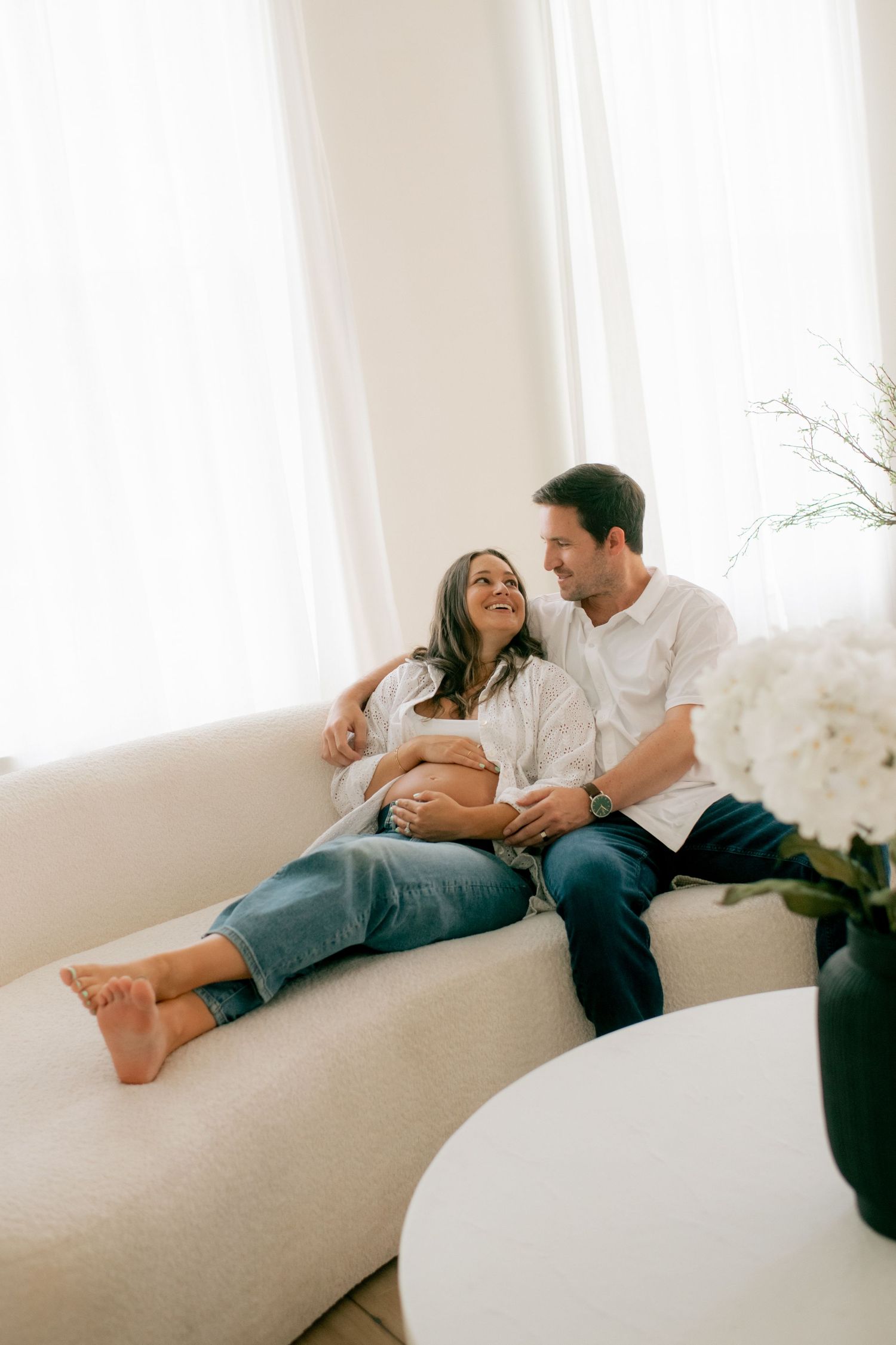 A couple shares intimate moments while relaxing on a white couch.