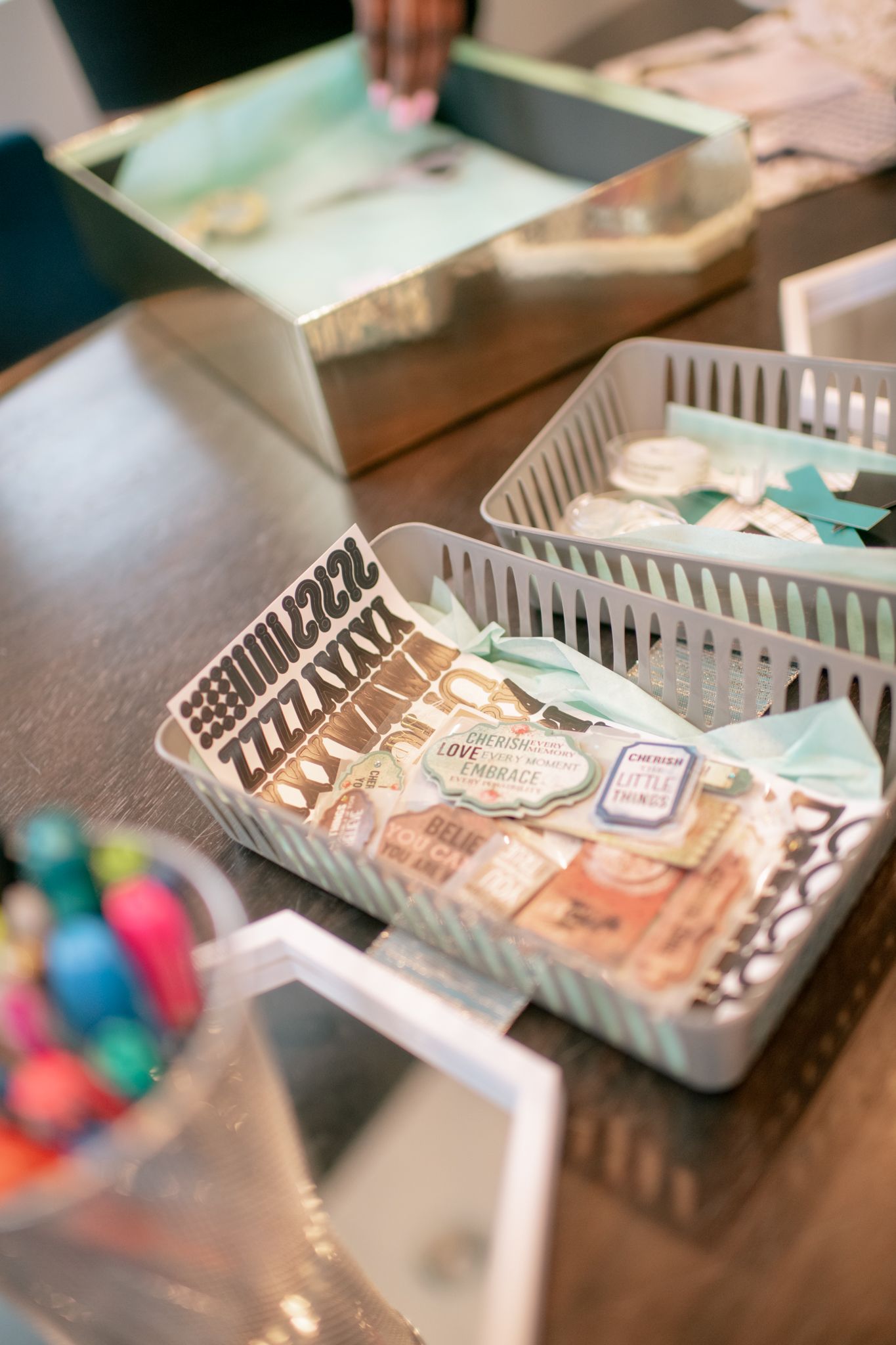 Shallow gray plastic trays containing various items arranged in a row on a dark wooden surface.