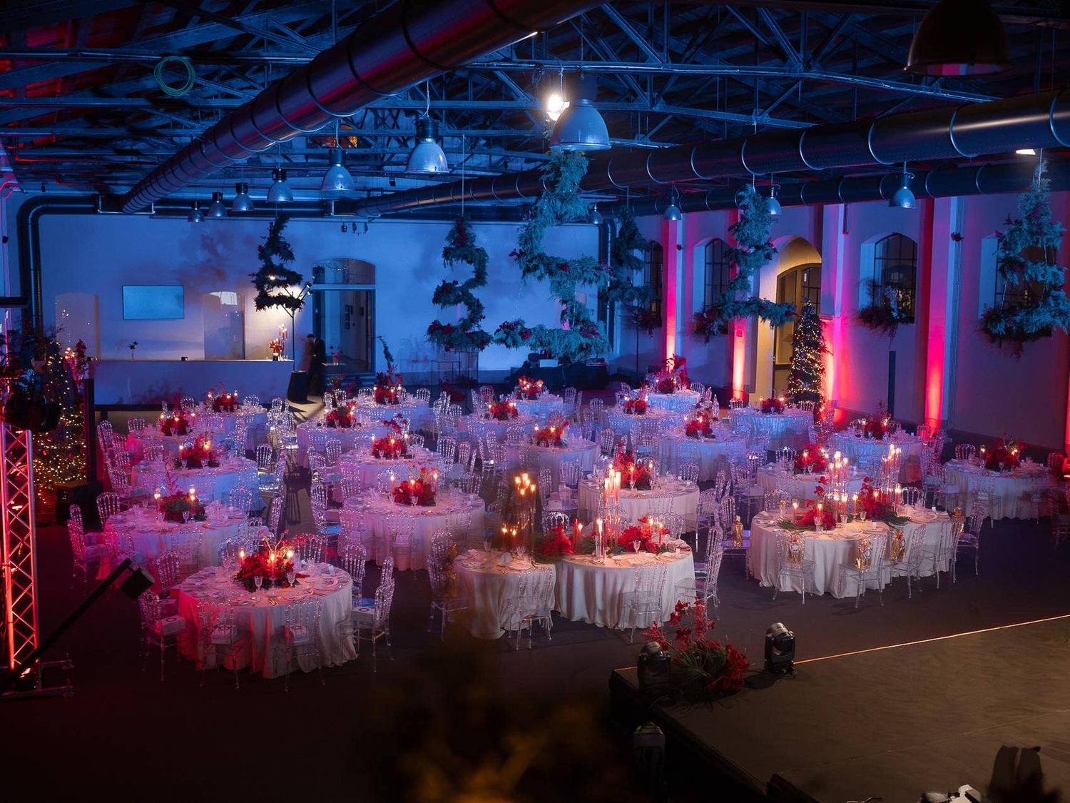 A panoramic view of an elegant wedding reception venue with white tables and dramatic pink and blue lighting.