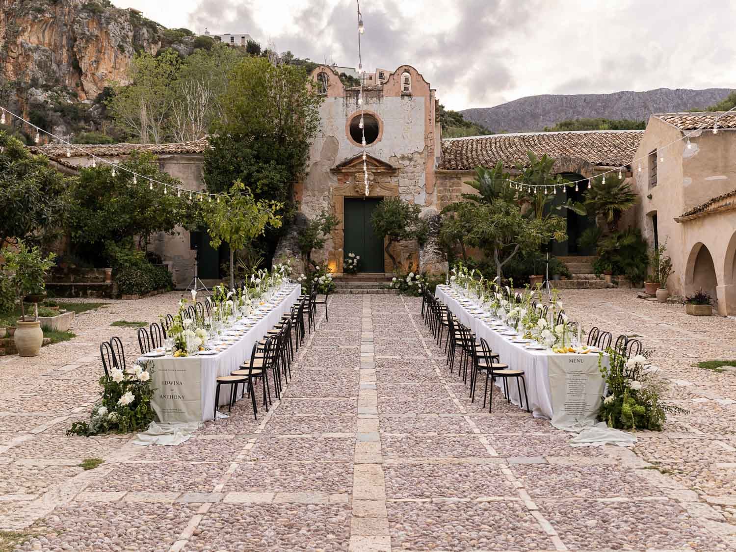 Long banquet table setup and mountain backdrop at Tonnara di Scopello for a Wedding in Sicily.